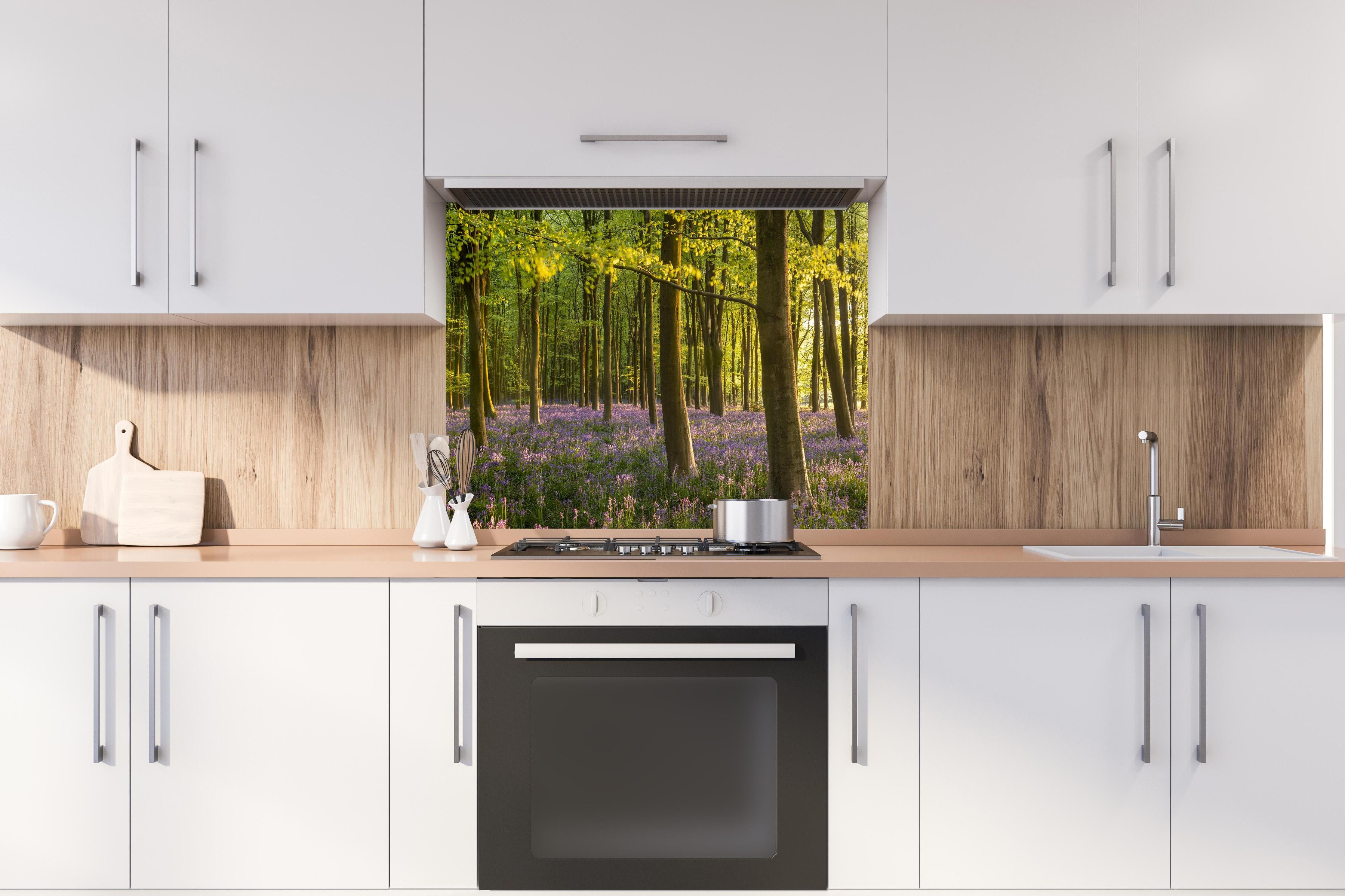 Spritzschutz - Schöner Blauglockenwald hinter einem Cerankochfeld zwischen Holz-Kochutensilien
