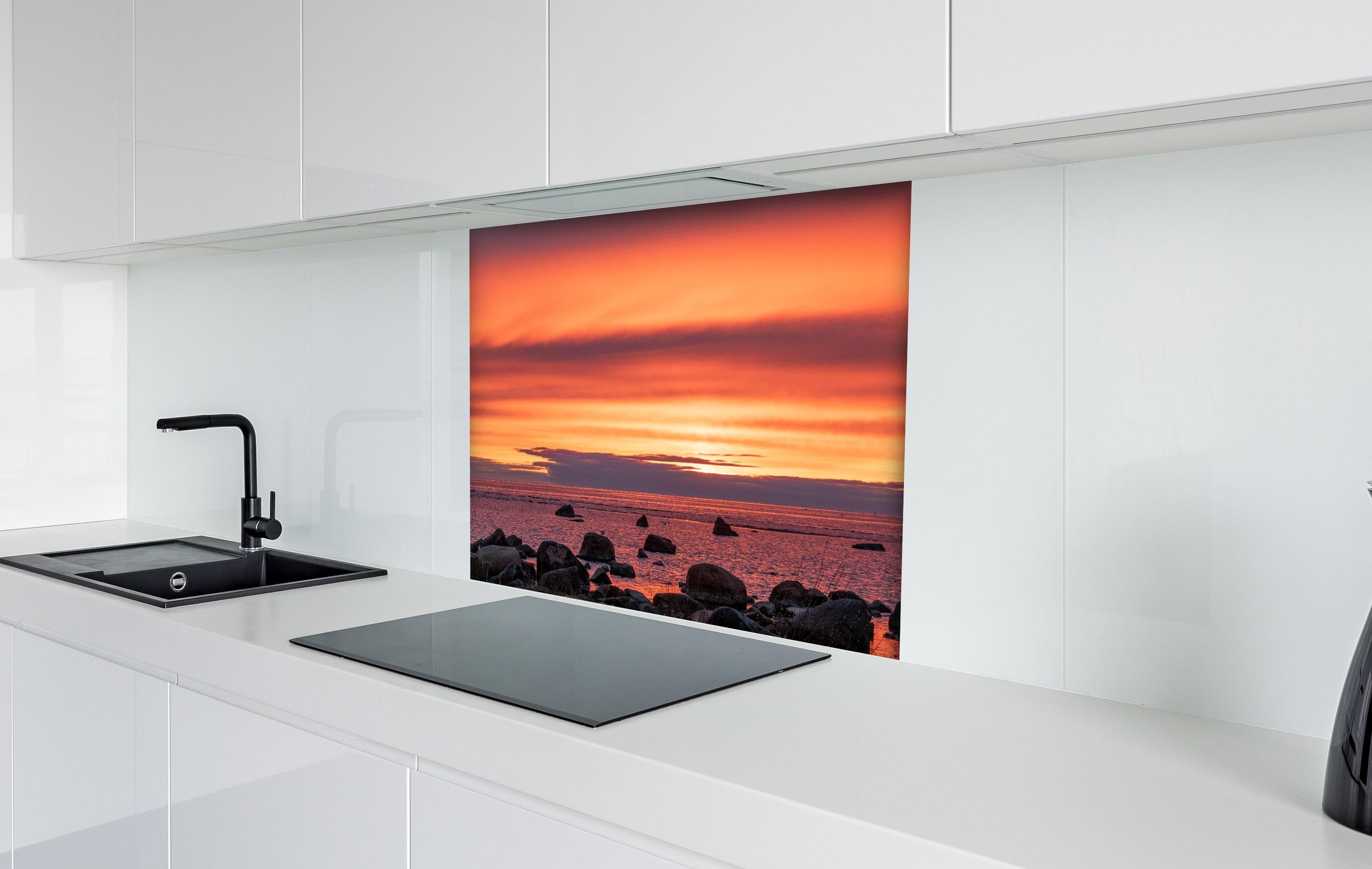 Spritzschutz - Schöner Sonnenuntergang am Meer hinter einem Cerankochfeld zwischen Holz-Kochutensilien
