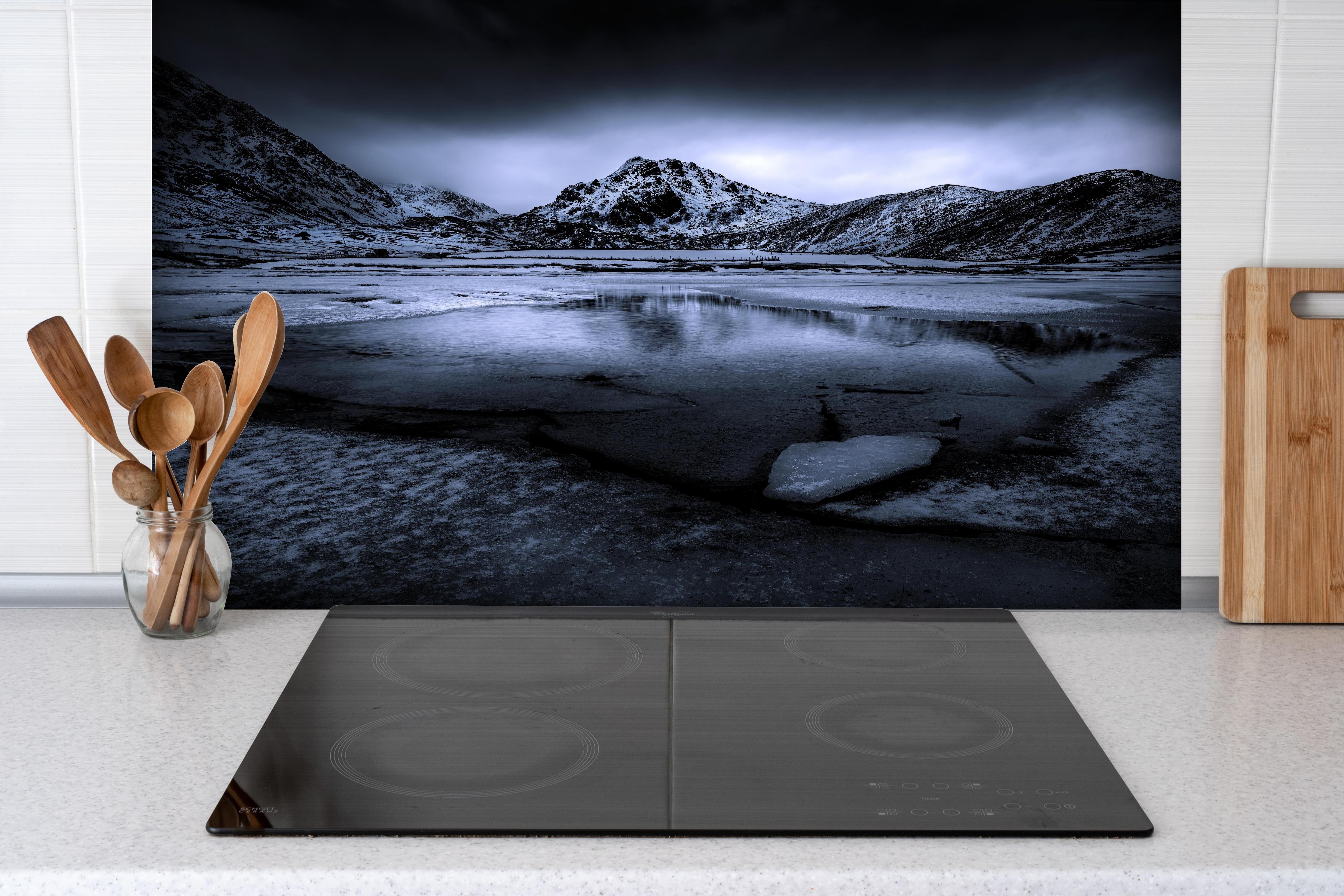 Spritzschutz - Schwarz-Weiß Winterlandschaft mit Bergspiegelung hinter einem Cerankochfeld zwischen Holz-Kochutensilien
