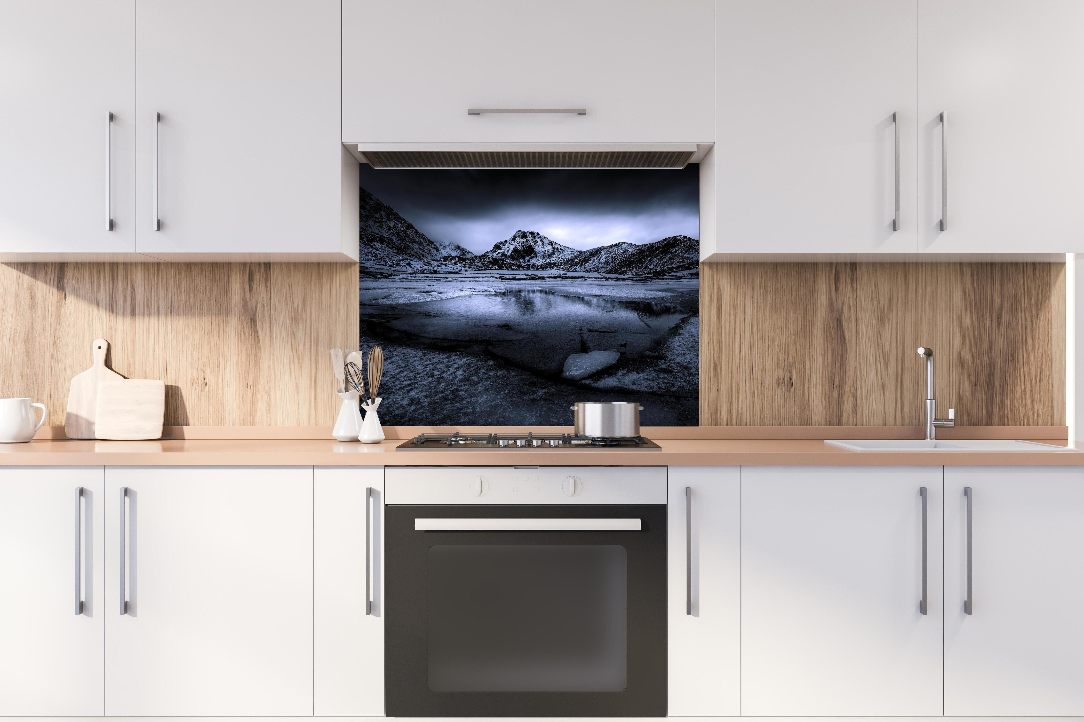 Spritzschutz - Schwarz-Weiß Winterlandschaft mit Bergspiegelung hinter einem Cerankochfeld zwischen Holz-Kochutensilien
