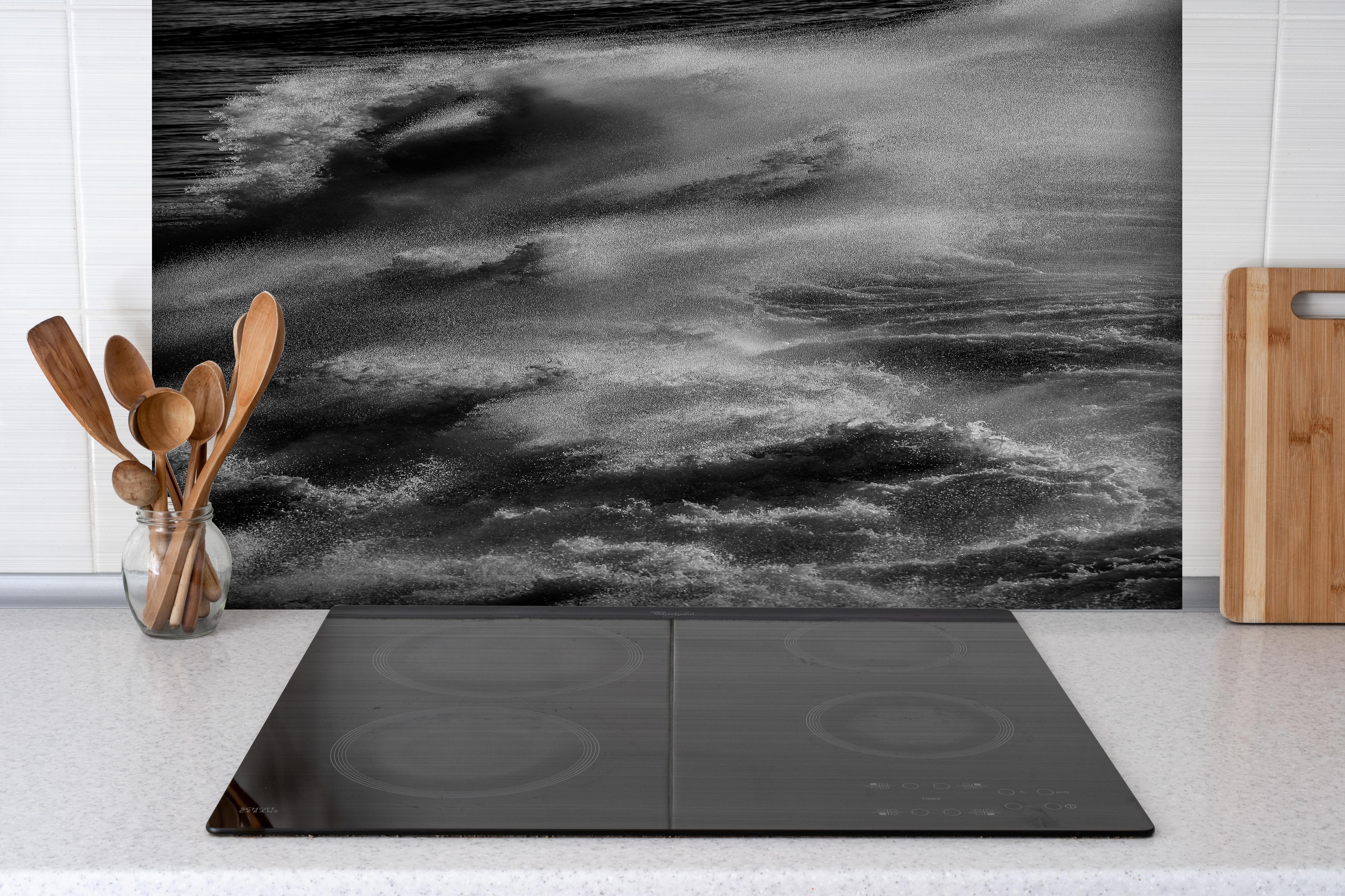 Spritzschutz - Schwarz-Weiße Ozeanwellen-Abstraktion hinter einem Cerankochfeld zwischen Holz-Kochutensilien
