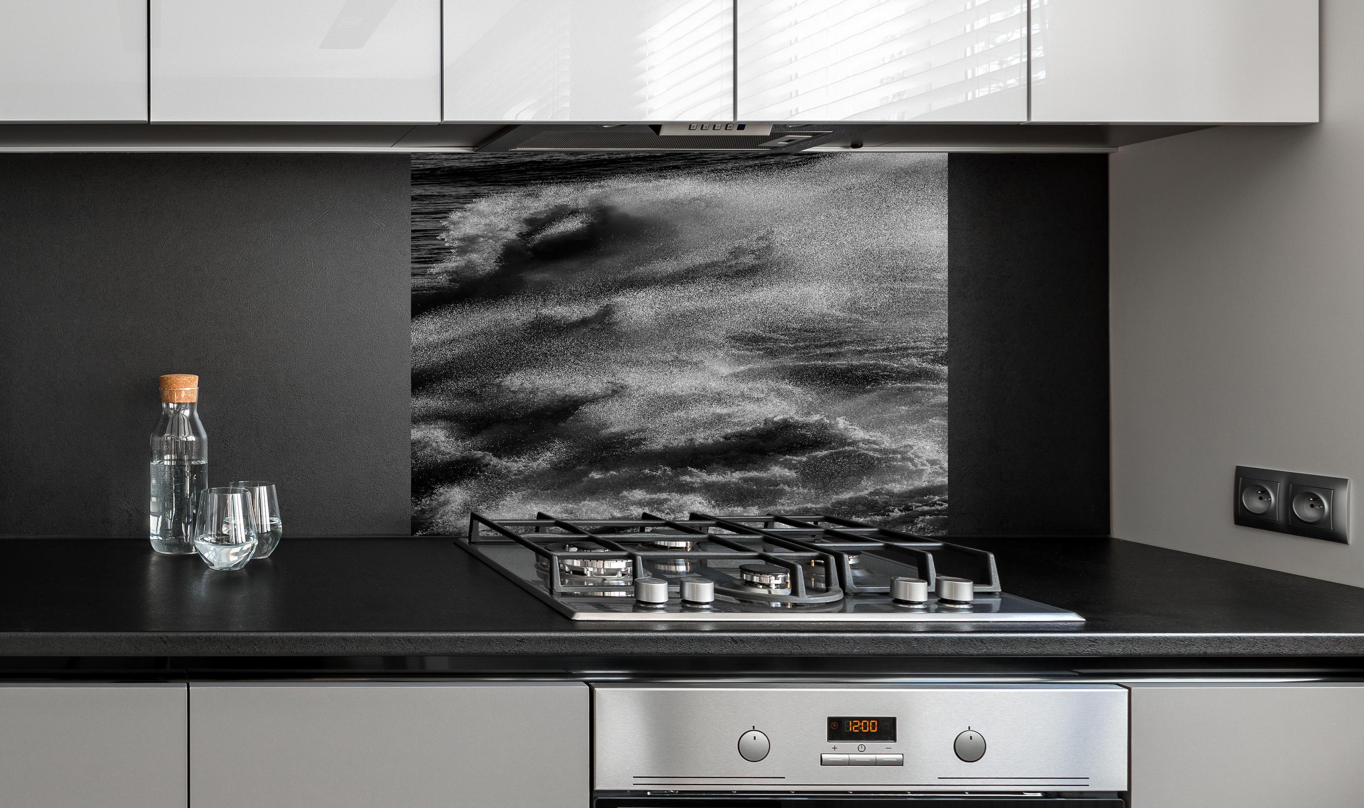 Spritzschutz - Schwarz-Weiße Ozeanwellen-Abstraktion hinter einem Cerankochfeld zwischen Holz-Kochutensilien
