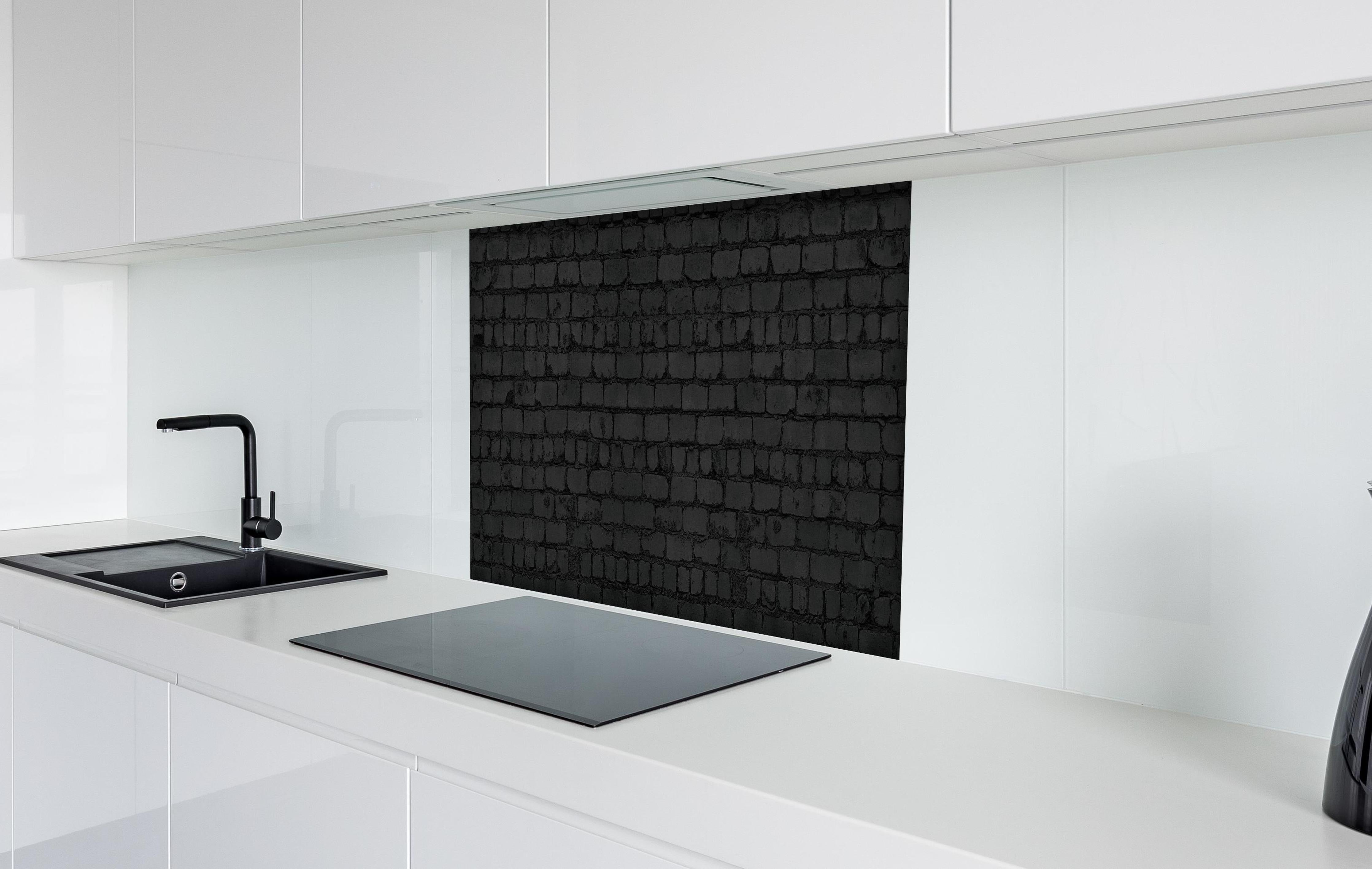 Spritzschutz - Schwarze raue Backsteinmauer hinter einem Cerankochfeld zwischen Holz-Kochutensilien
