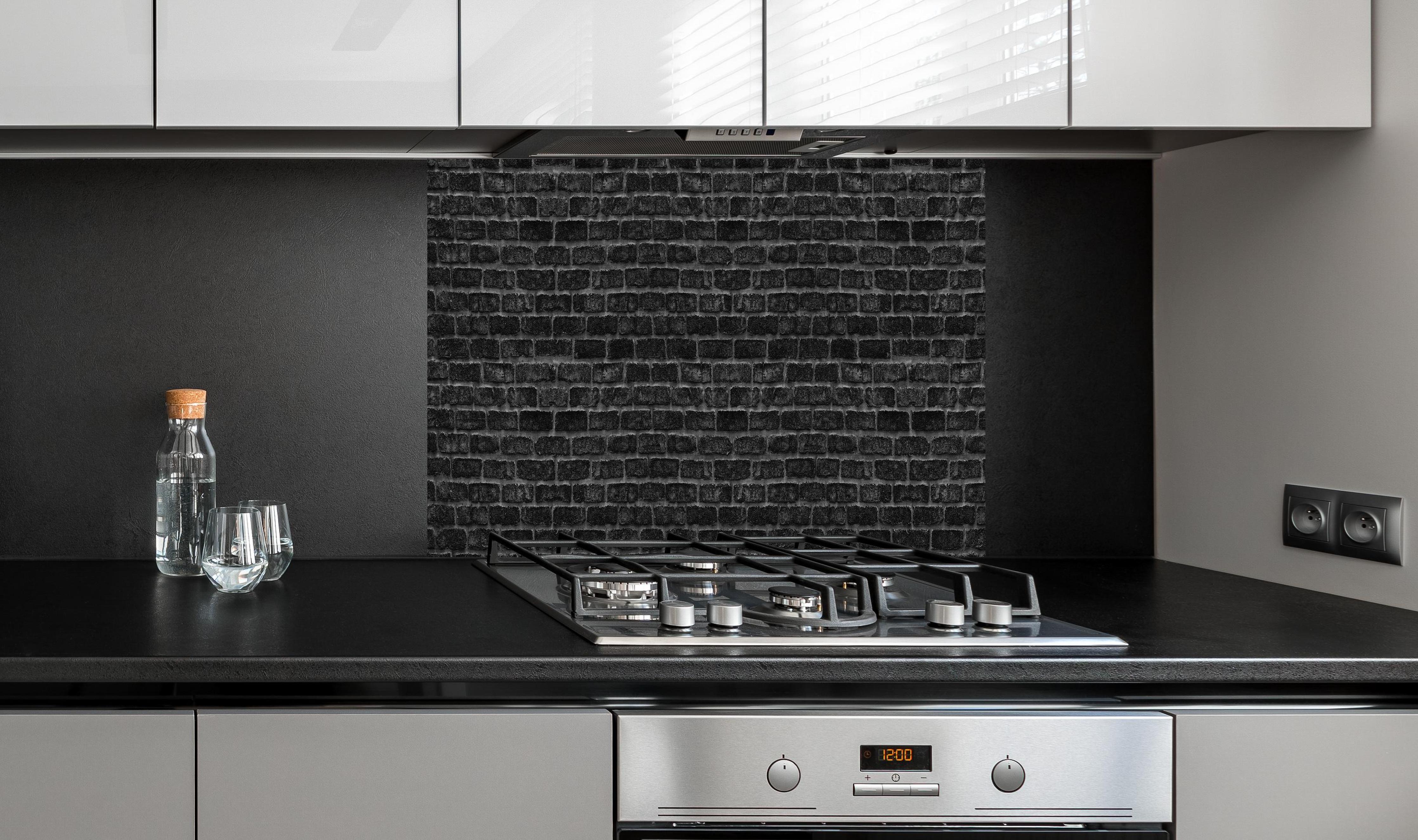 Spritzschutz - Schwarze schlichte Ziegelwand hinter einem Cerankochfeld zwischen Holz-Kochutensilien
