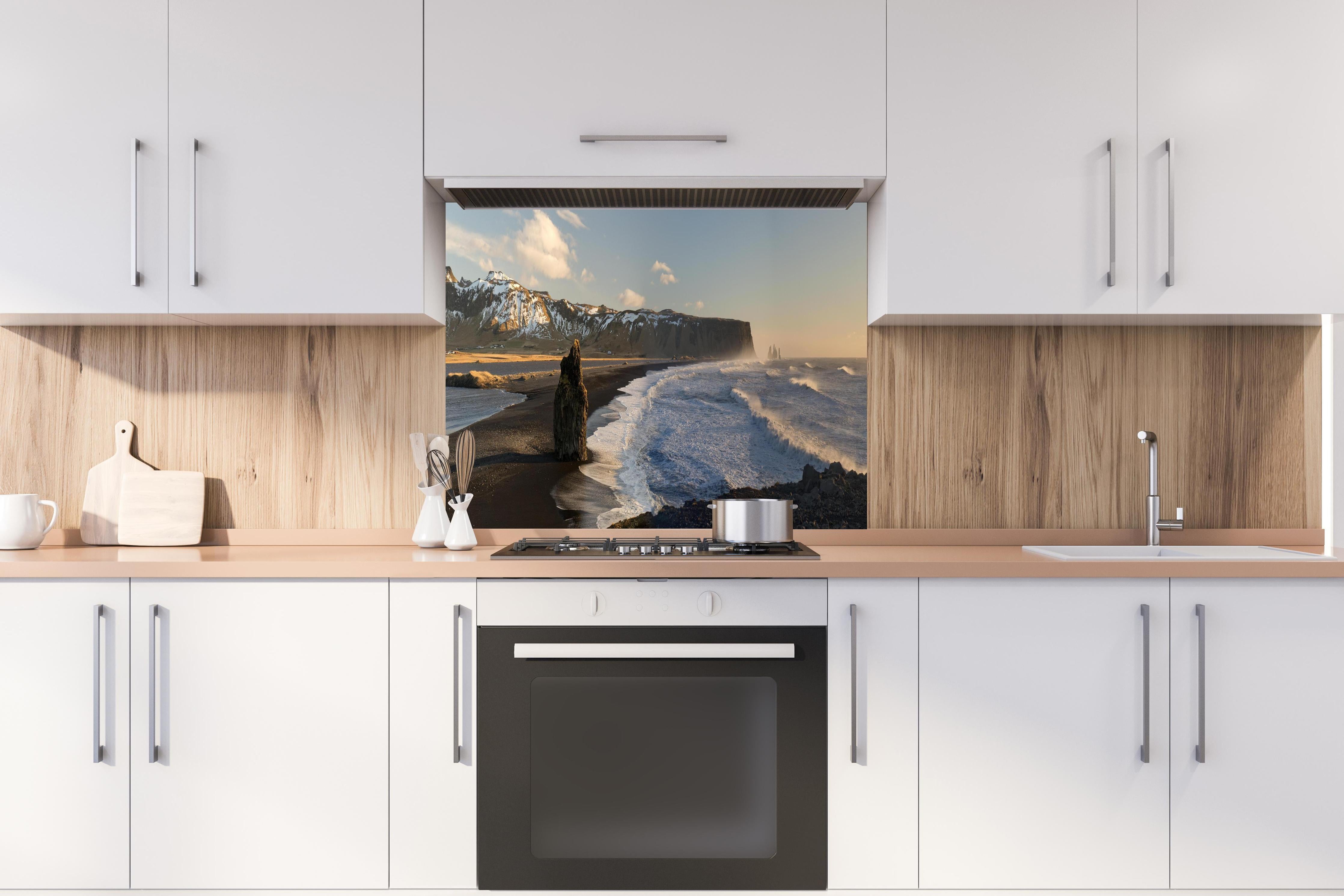 Spritzschutz - Schwarzer Strand von Dyrholaey hinter einem Cerankochfeld zwischen Holz-Kochutensilien
