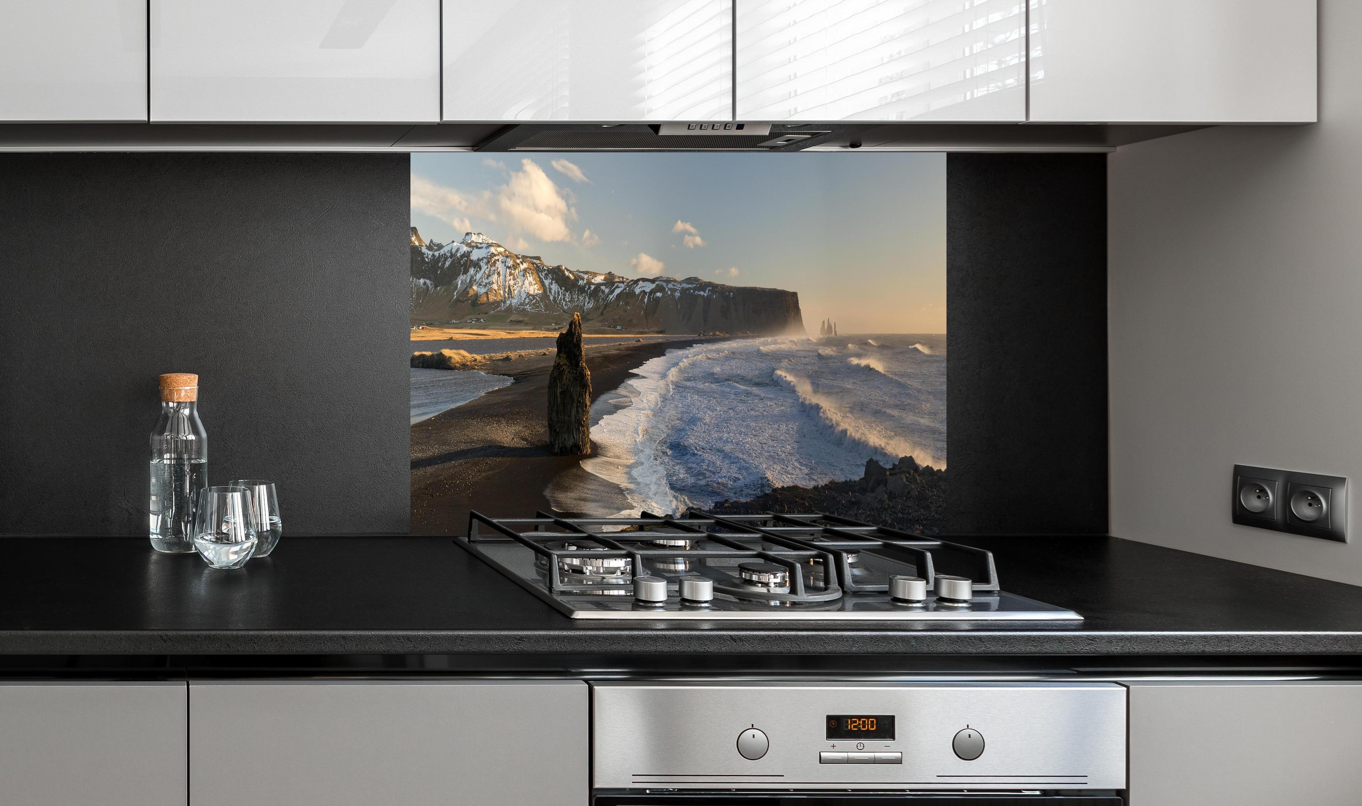 Spritzschutz - Schwarzer Strand von Dyrholaey hinter einem Cerankochfeld zwischen Holz-Kochutensilien
