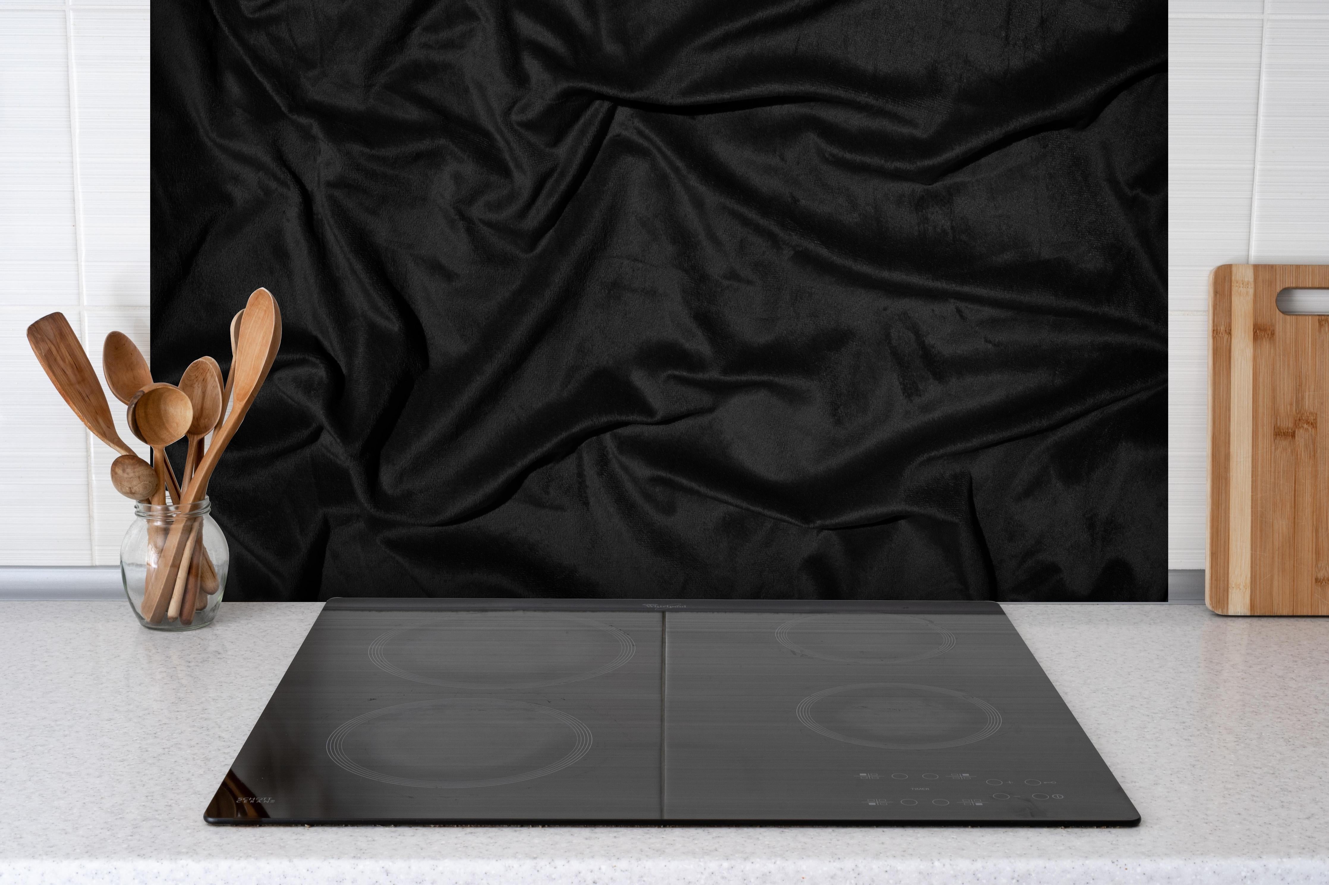 Spritzschutz - Schwarzes Satin Seiden Tuch hinter einem Cerankochfeld zwischen Holz-Kochutensilien
