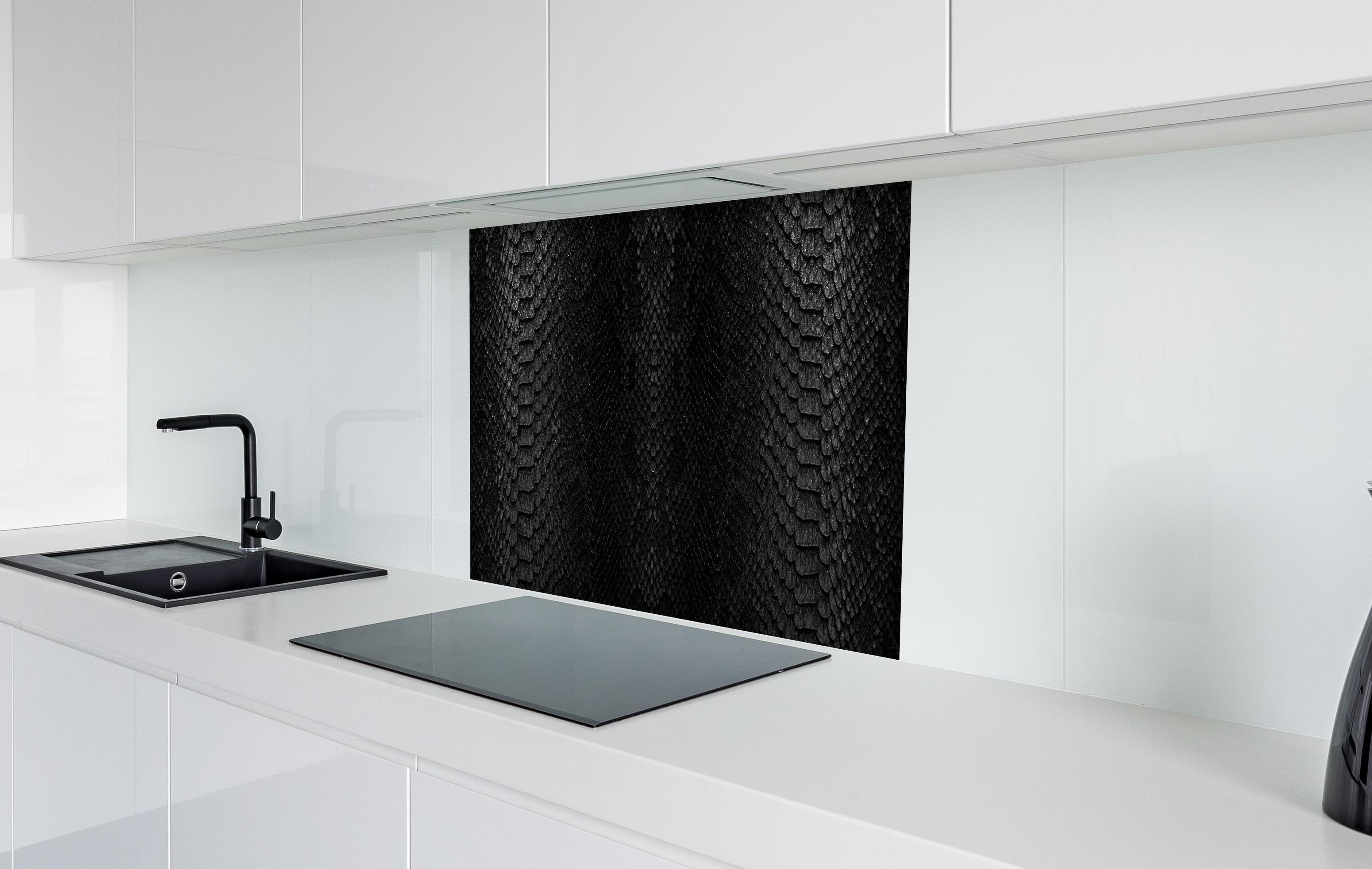 Spritzschutz - Schwarzes Schlangenhautmuster hinter einem Cerankochfeld zwischen Holz-Kochutensilien
