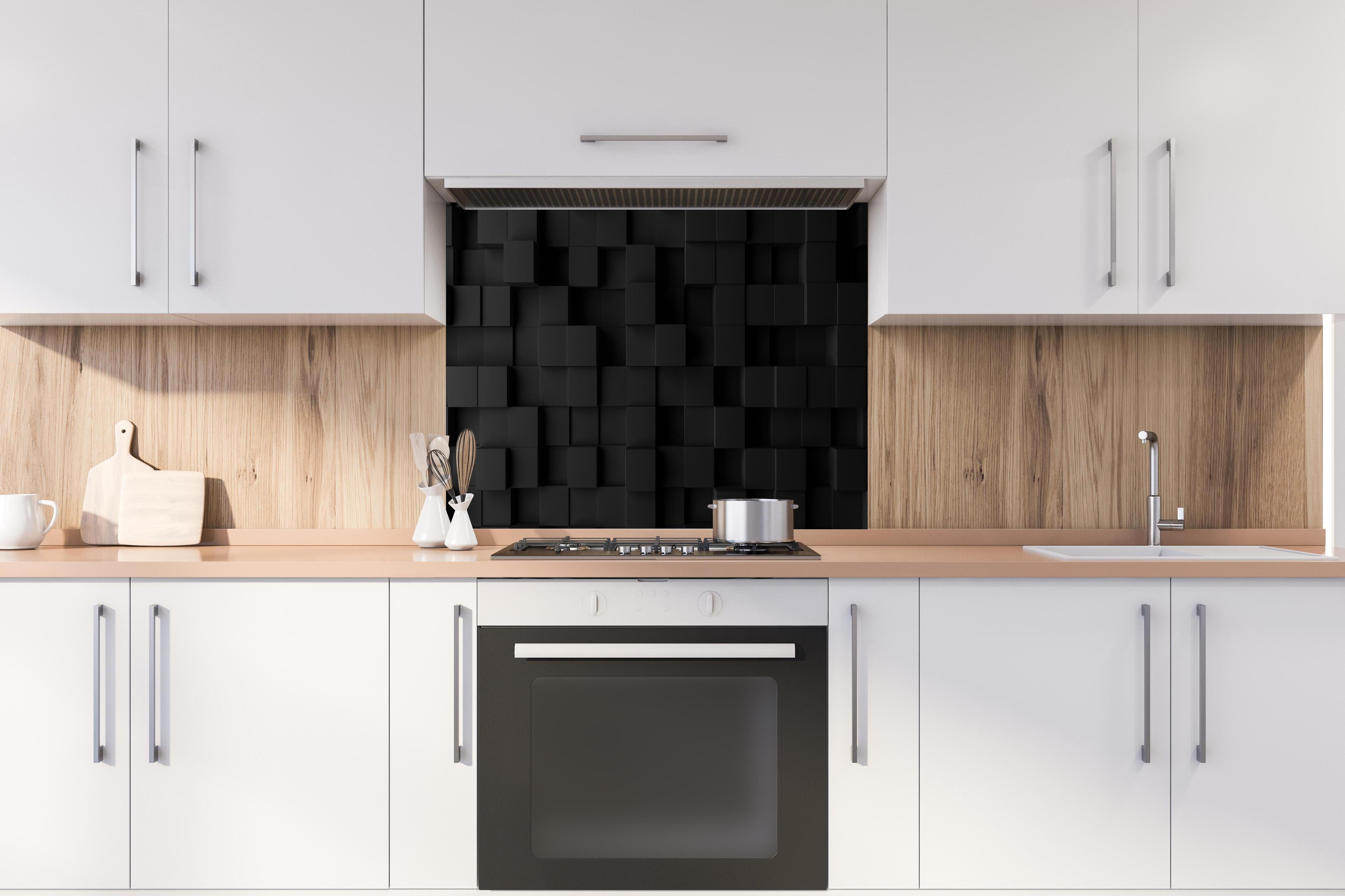 Spritzschutz - Schwarzes Vierecks Muster hinter einem Cerankochfeld zwischen Holz-Kochutensilien
