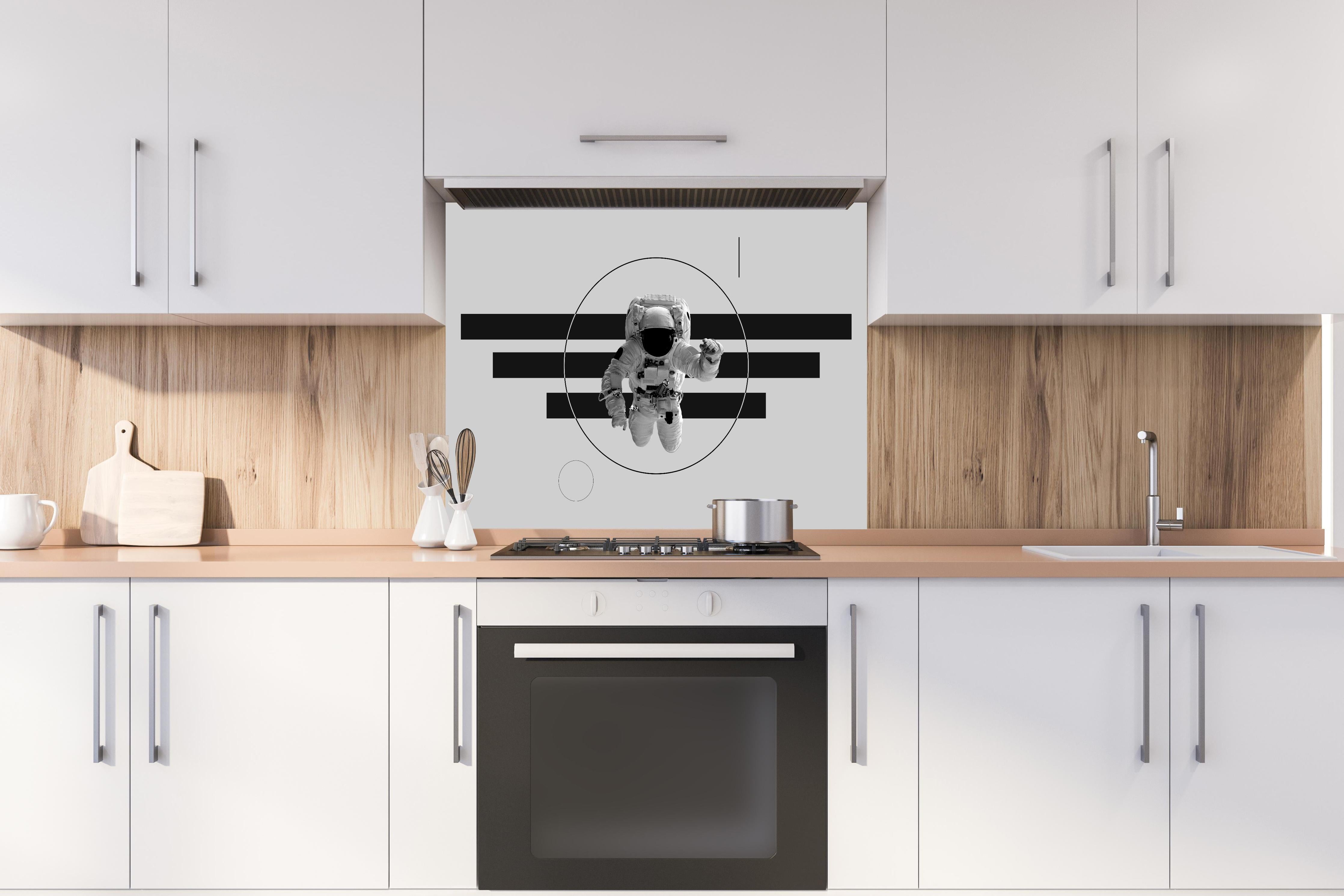 Spritzschutz - Schwebender Astronaut, Grau-Schwarzes Design hinter einem Cerankochfeld zwischen Holz-Kochutensilien
