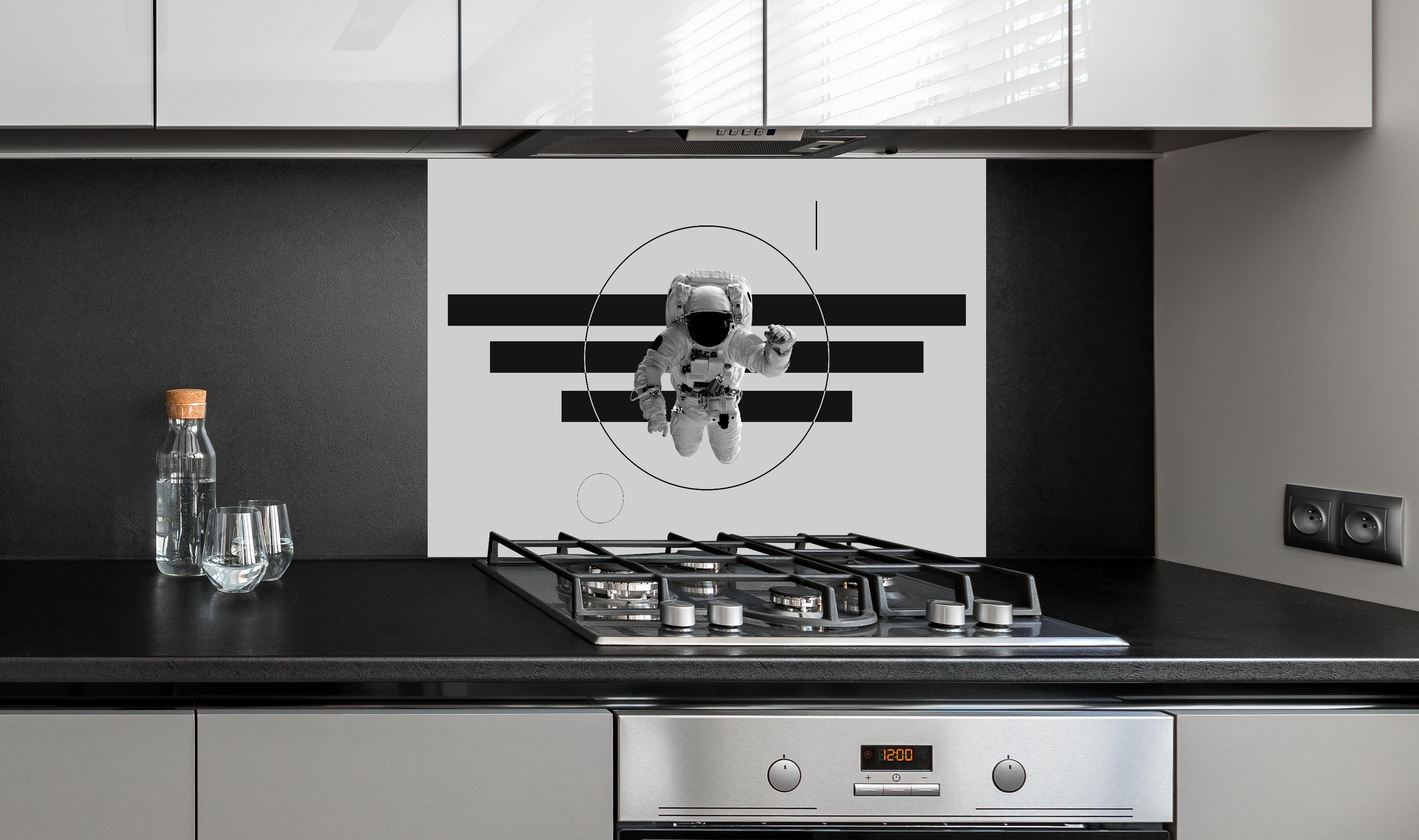 Spritzschutz - Schwebender Astronaut, Grau-Schwarzes Design hinter einem Cerankochfeld zwischen Holz-Kochutensilien
