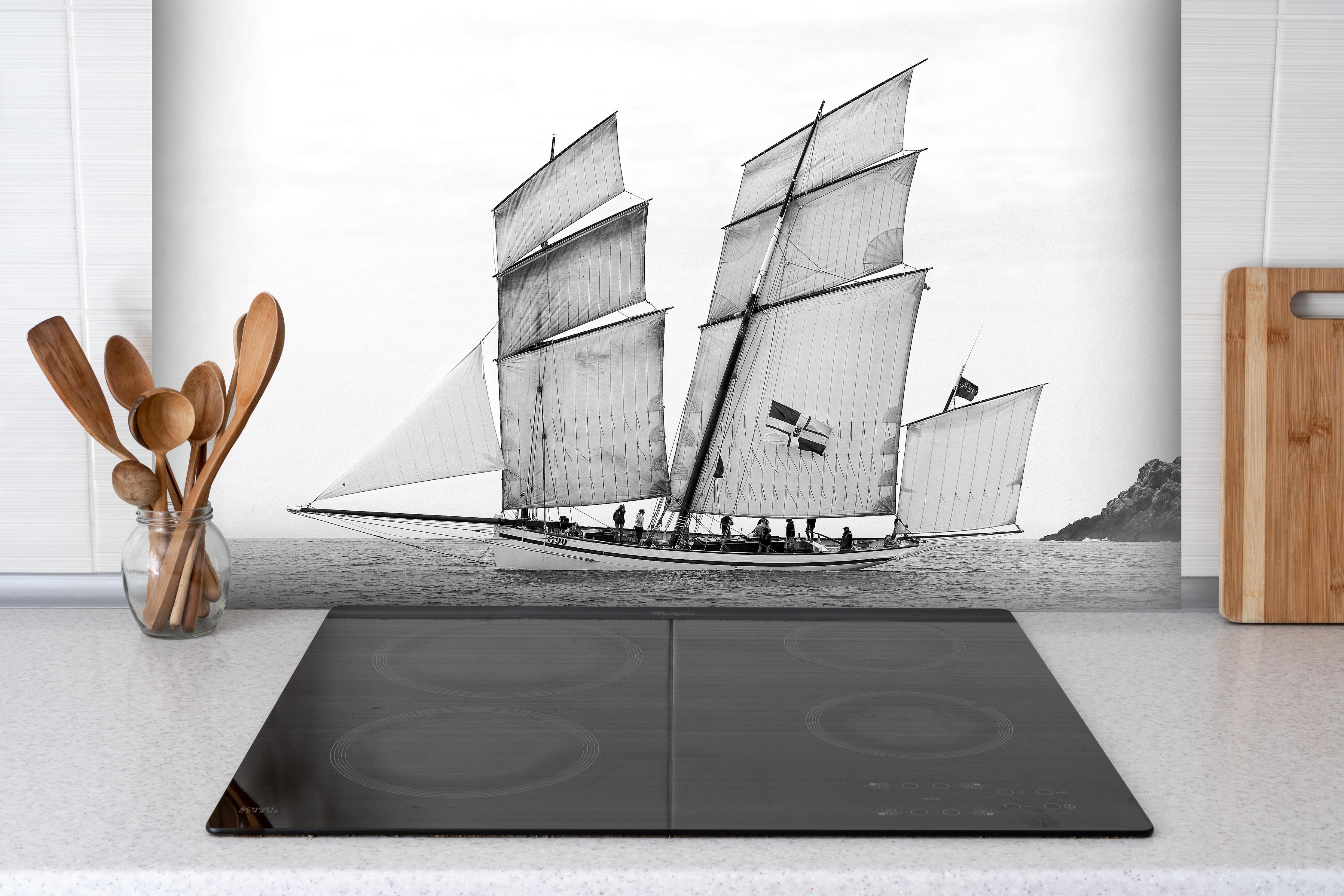 Spritzschutz - Segelboot auf dem Meer hinter einem Cerankochfeld zwischen Holz-Kochutensilien
