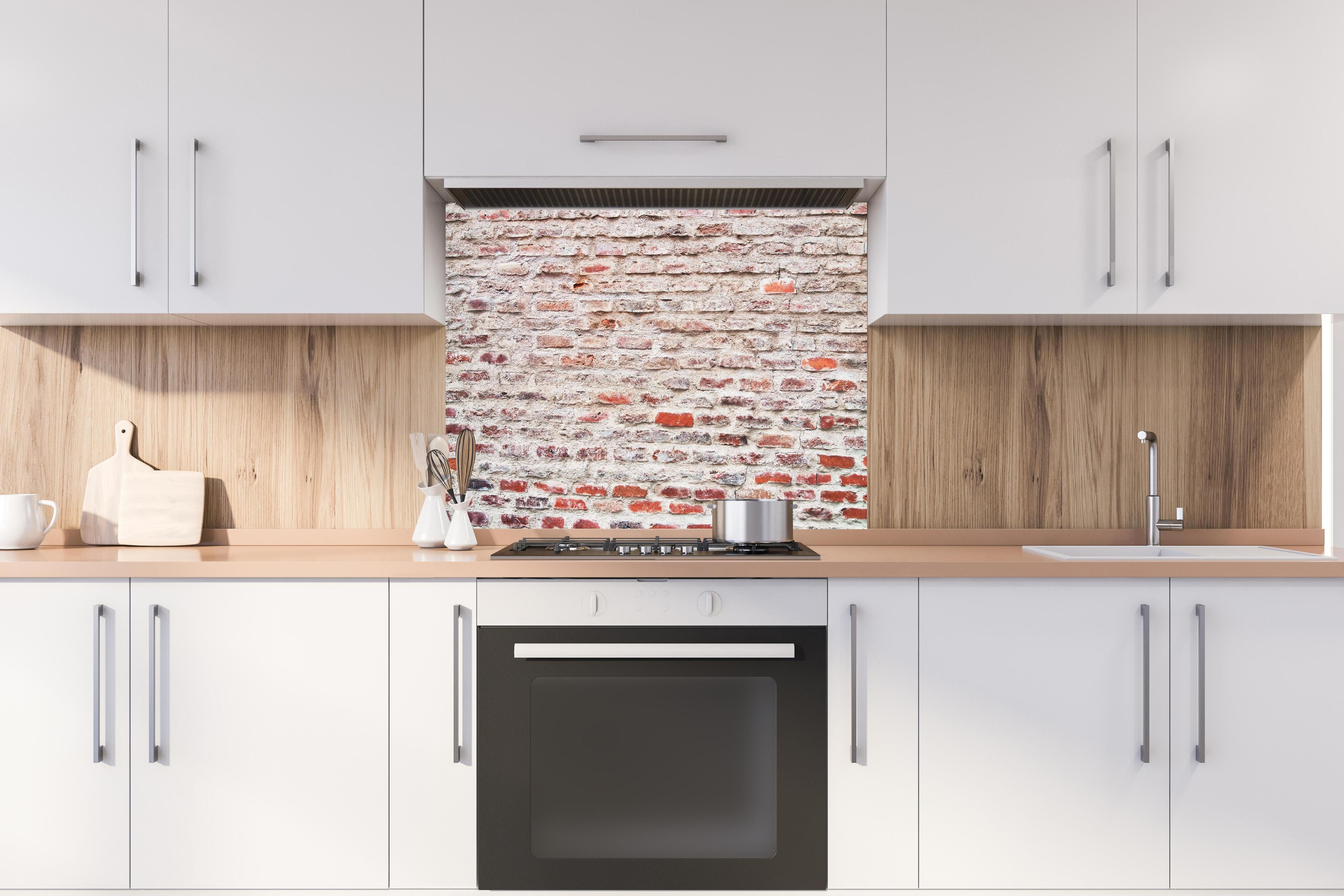 Spritzschutz - Sehr alte kaputte Steinmauer hinter einem Cerankochfeld zwischen Holz-Kochutensilien
