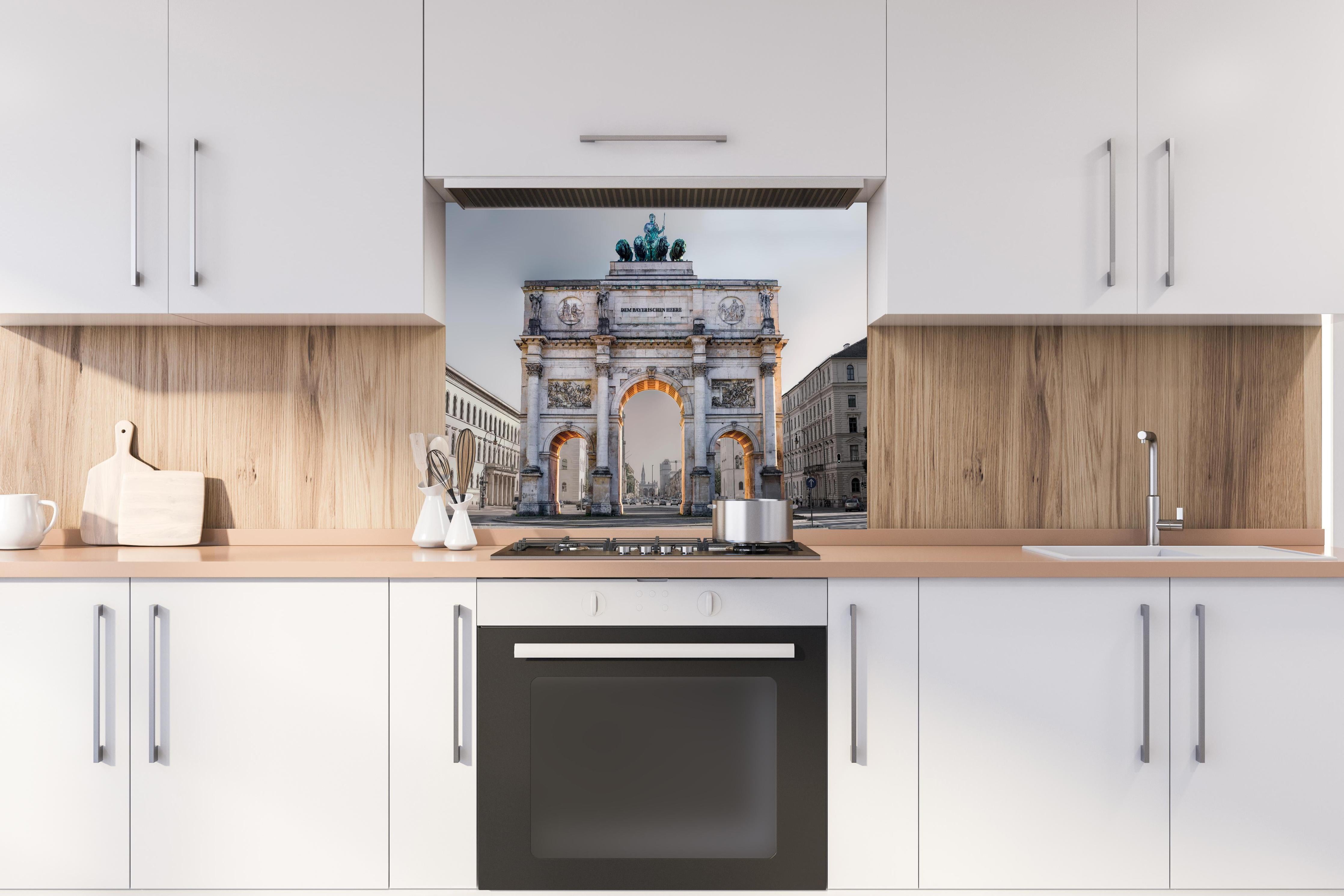 Spritzschutz - Siegestor in München an der Leopoldstraße hinter einem Cerankochfeld zwischen Holz-Kochutensilien
