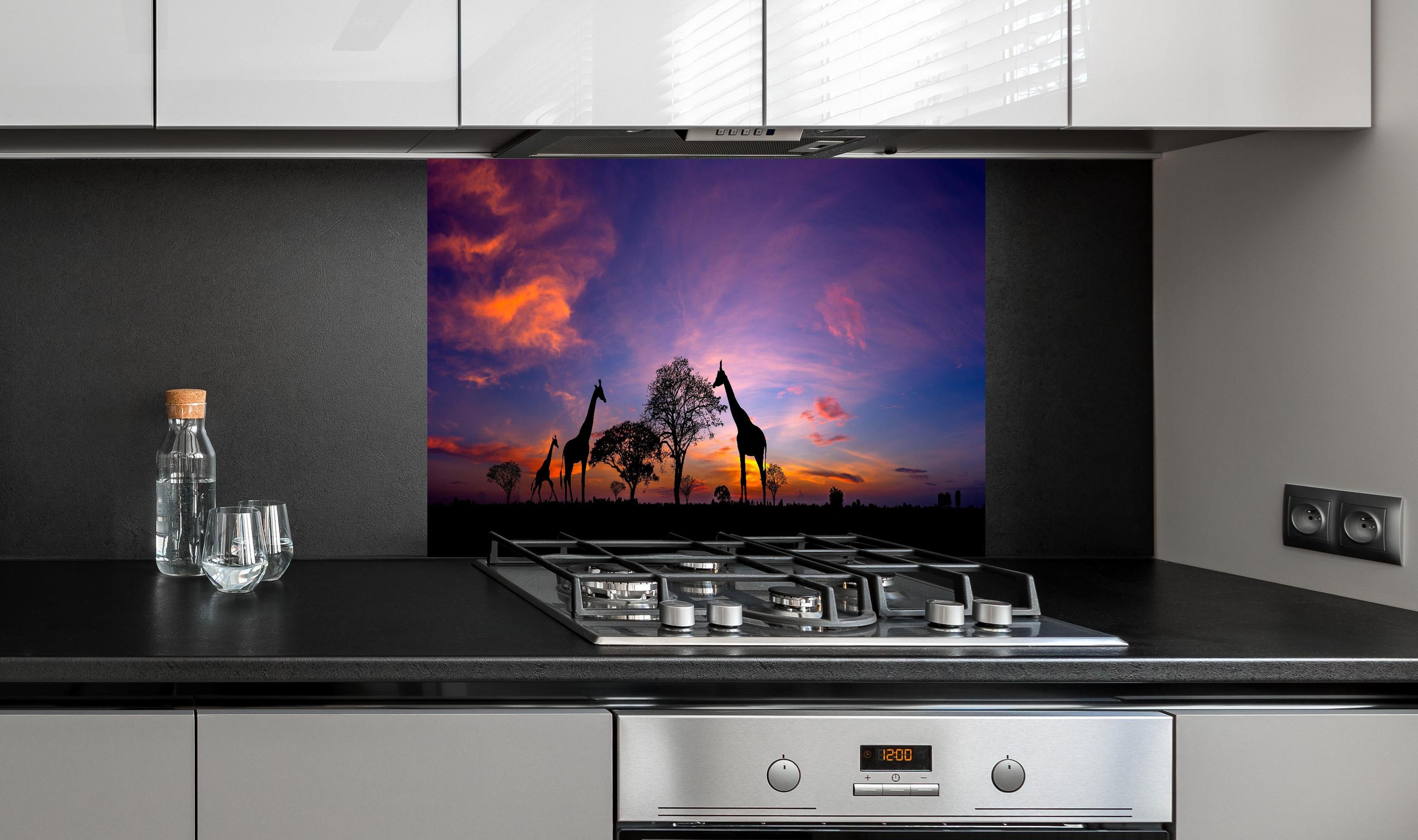 Spritzschutz - Silhouette - Giraffenfamilie bei Sonnenuntergang hinter einem Cerankochfeld zwischen Holz-Kochutensilien
