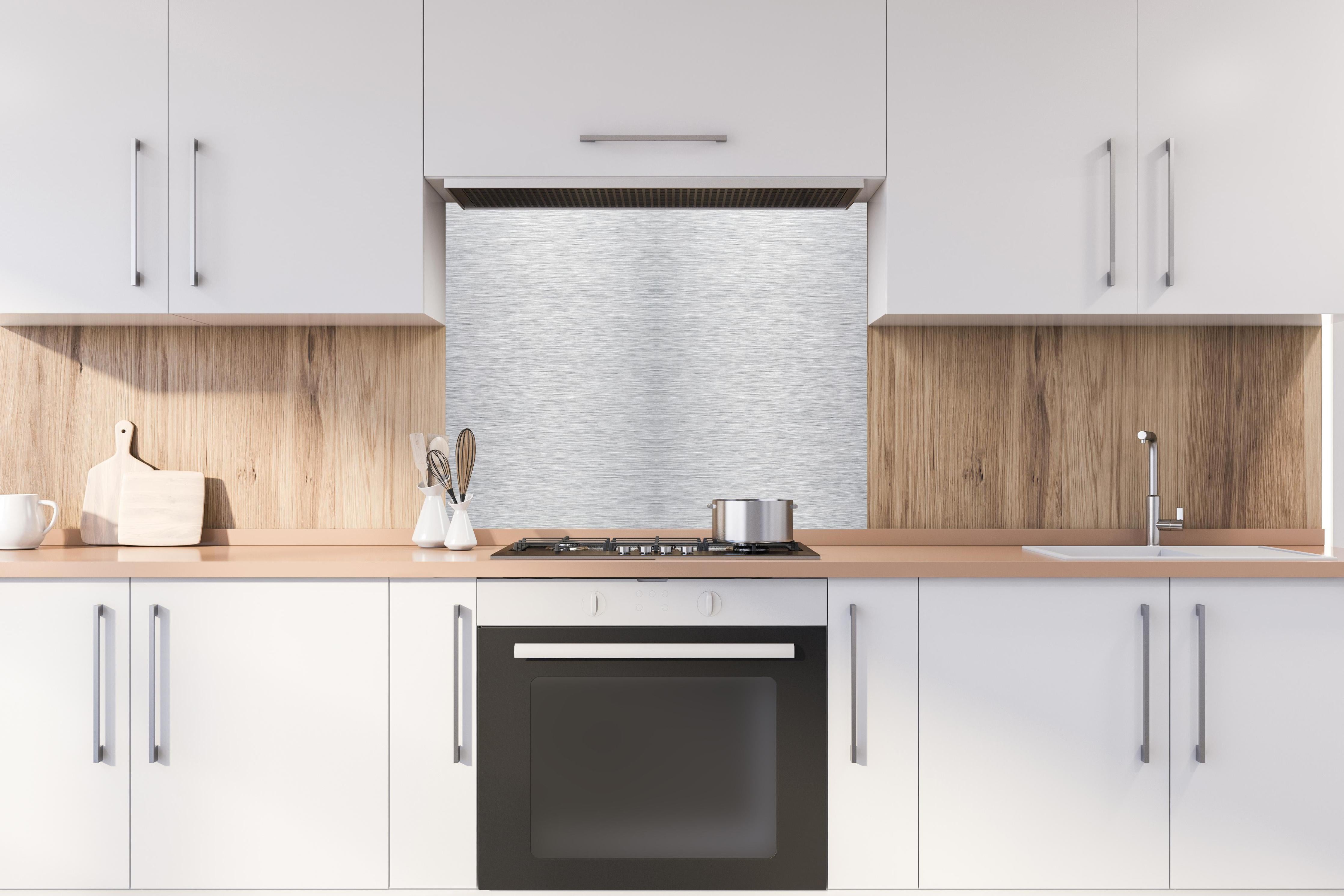 Spritzschutz - Skip hinter einem Cerankochfeld zwischen Holz-Kochutensilien
