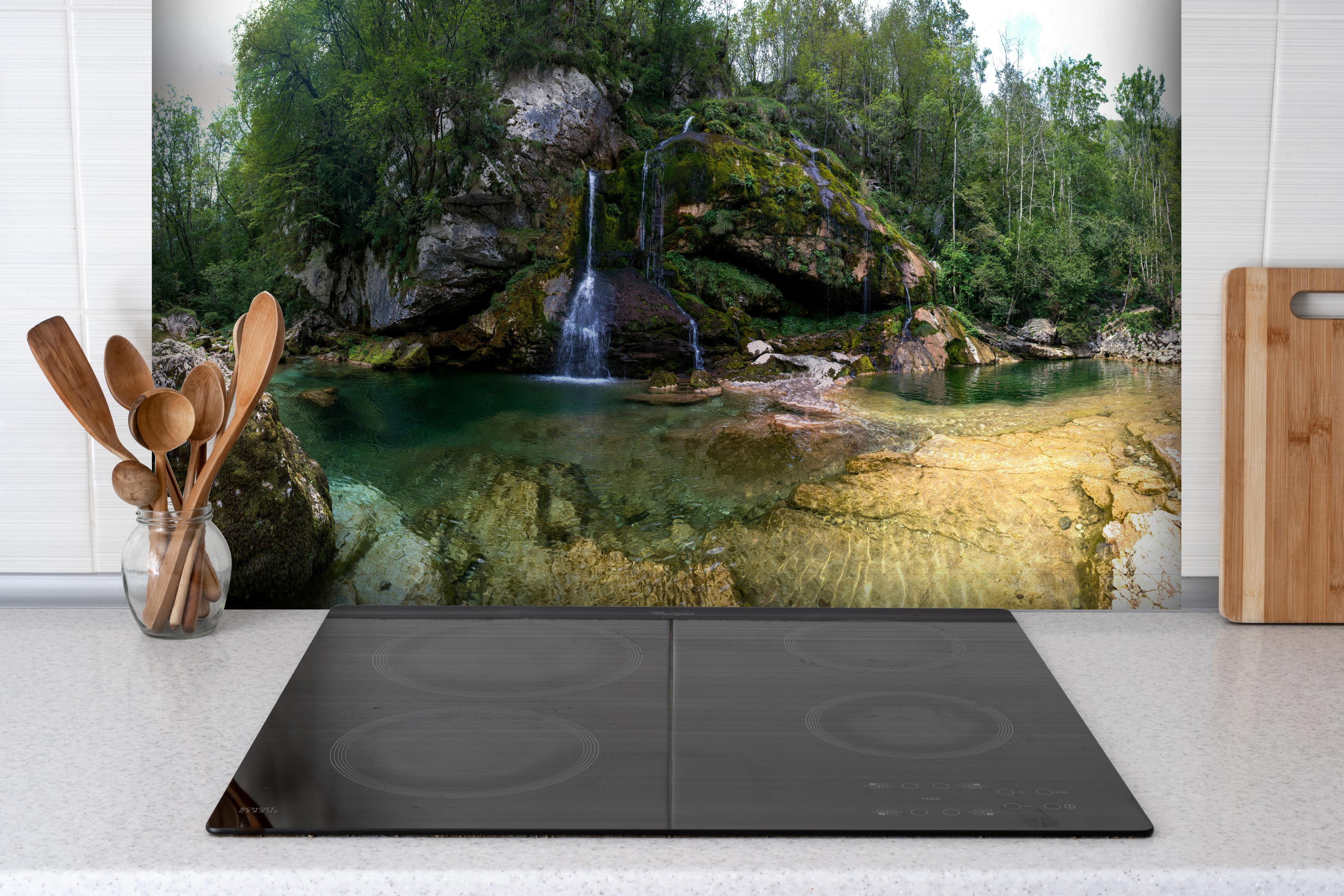 Spritzschutz - Sommerliche Atmosphäre in den Slowenischen Alpen hinter einem Cerankochfeld zwischen Holz-Kochutensilien
