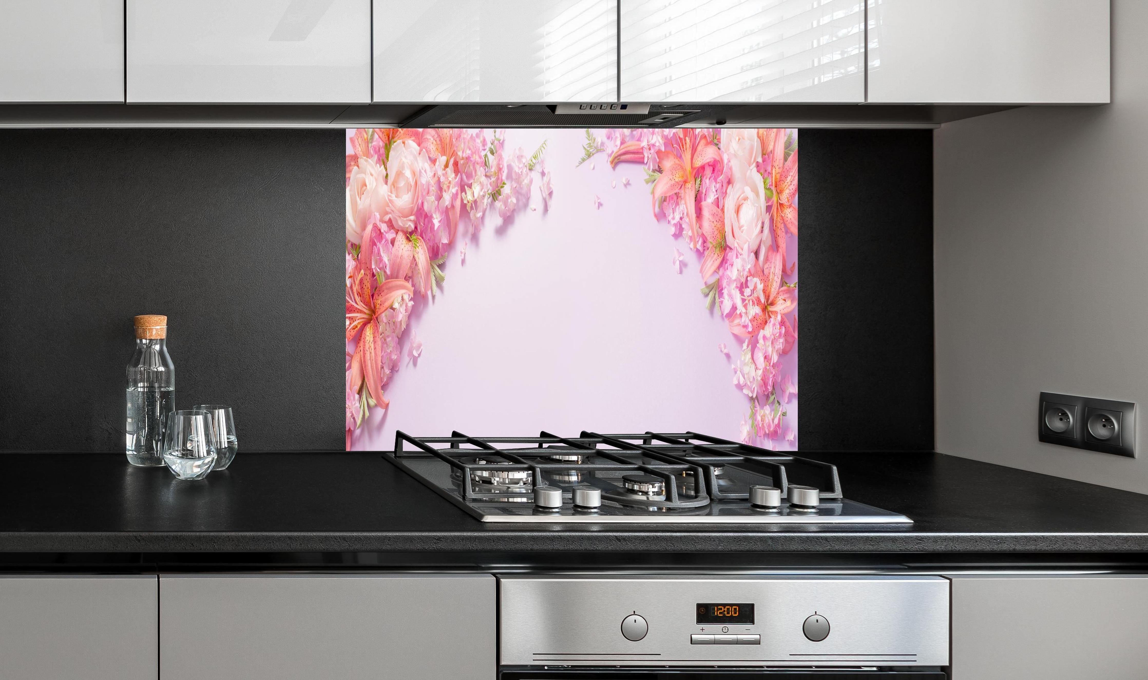 Spritzschutz - Sommerliche Blumenarrangements auf Papier hinter einem Cerankochfeld zwischen Holz-Kochutensilien
