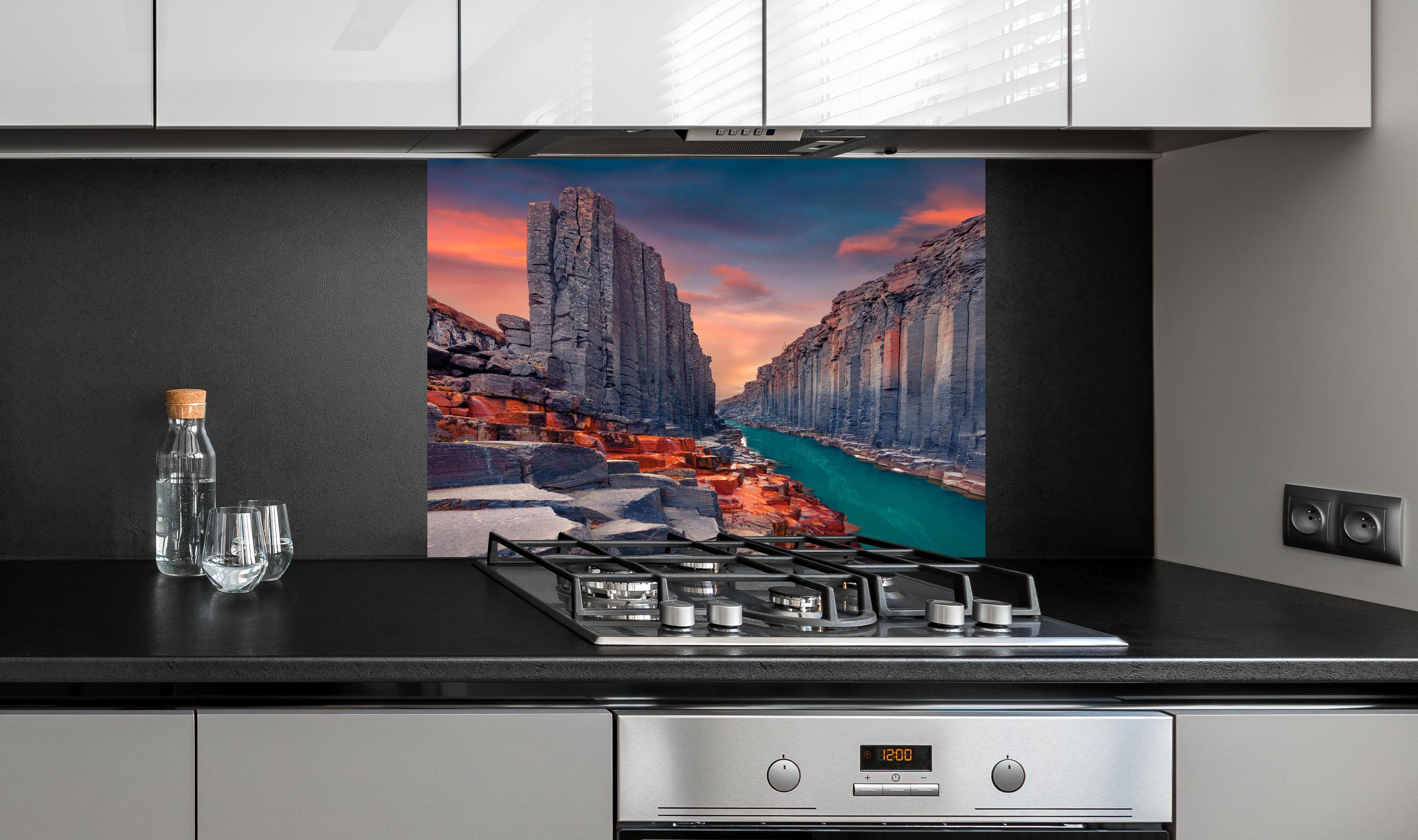 Spritzschutz - Sommerlicher Sonnenaufgang - Studlagil-Schlucht hinter einem Cerankochfeld zwischen Holz-Kochutensilien
