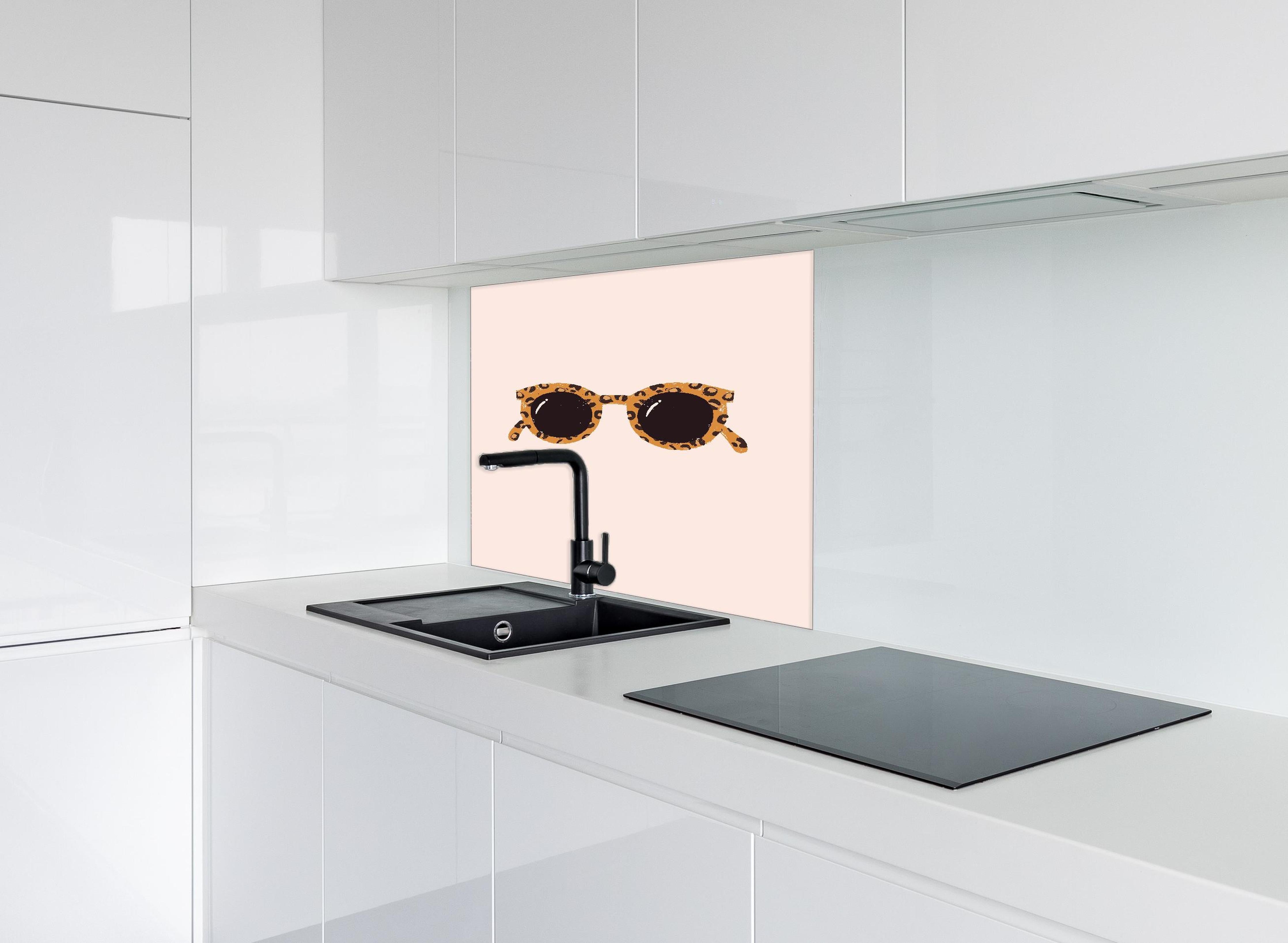 Spritzschutz - Sonnenbrille - Leopardenmuster hinter einem Cerankochfeld zwischen Holz-Kochutensilien
