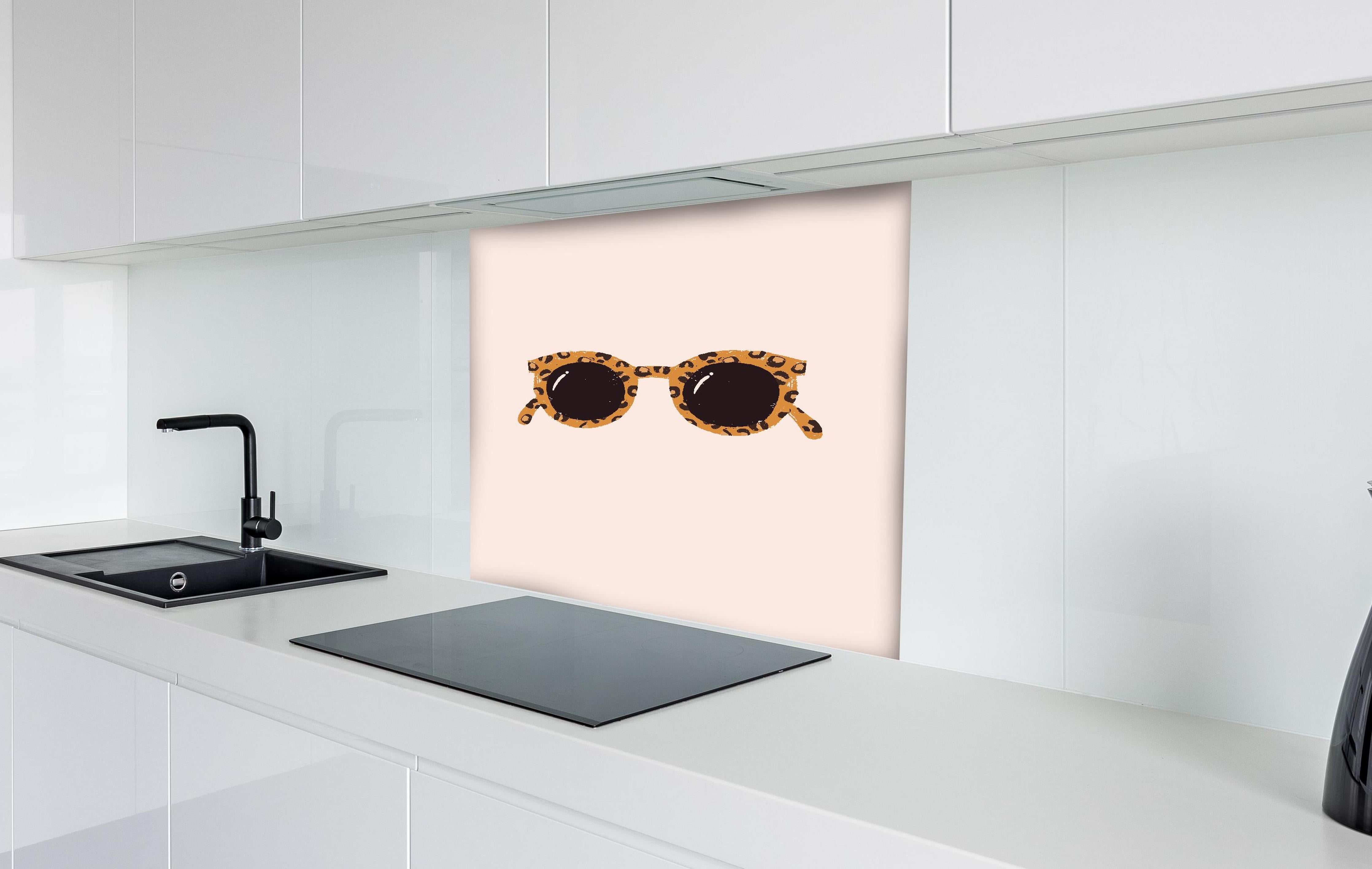 Spritzschutz - Sonnenbrille - Leopardenmuster hinter einem Cerankochfeld zwischen Holz-Kochutensilien
