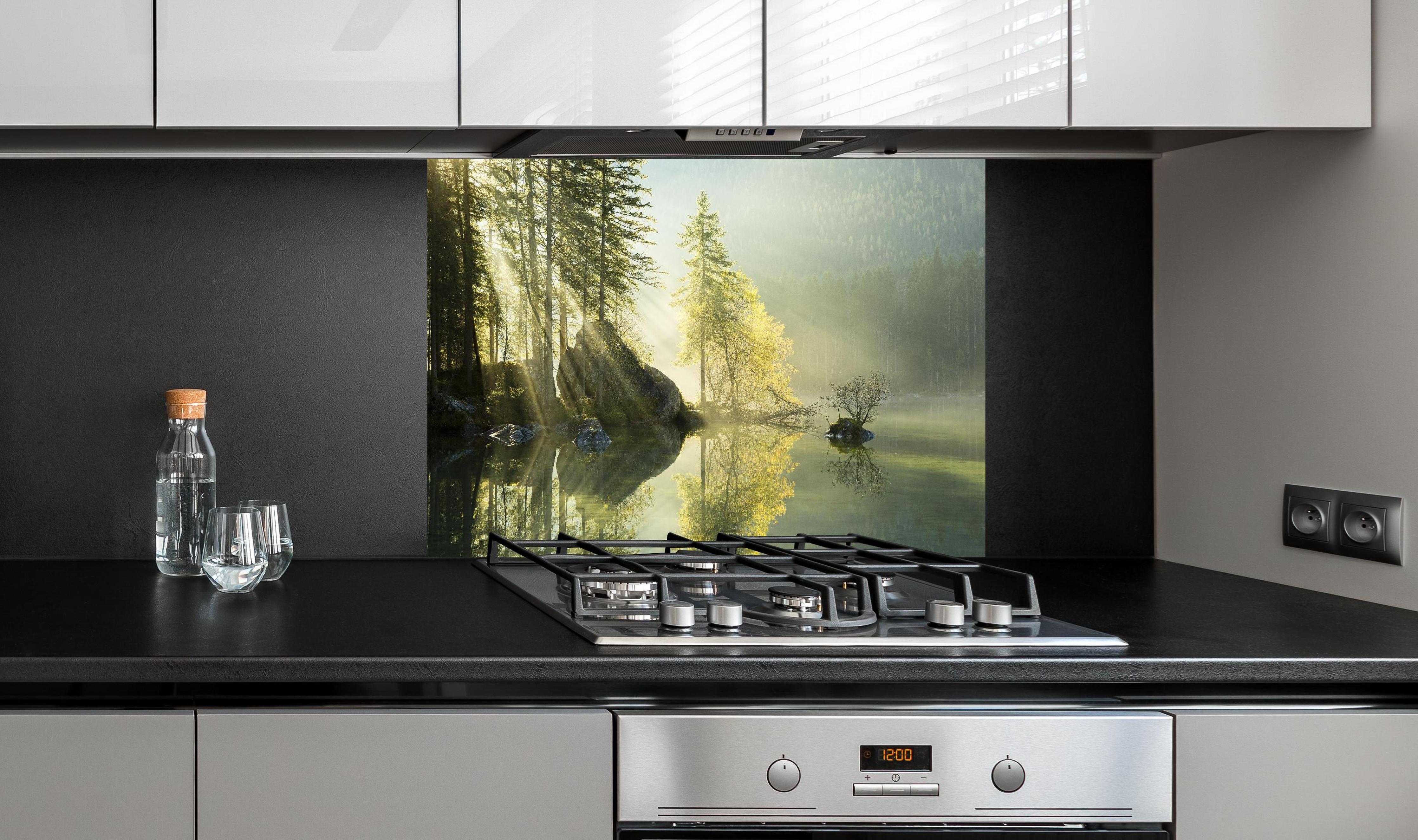 Spritzschutz - Sonnenstrahlen im See hinter einem Cerankochfeld zwischen Holz-Kochutensilien
