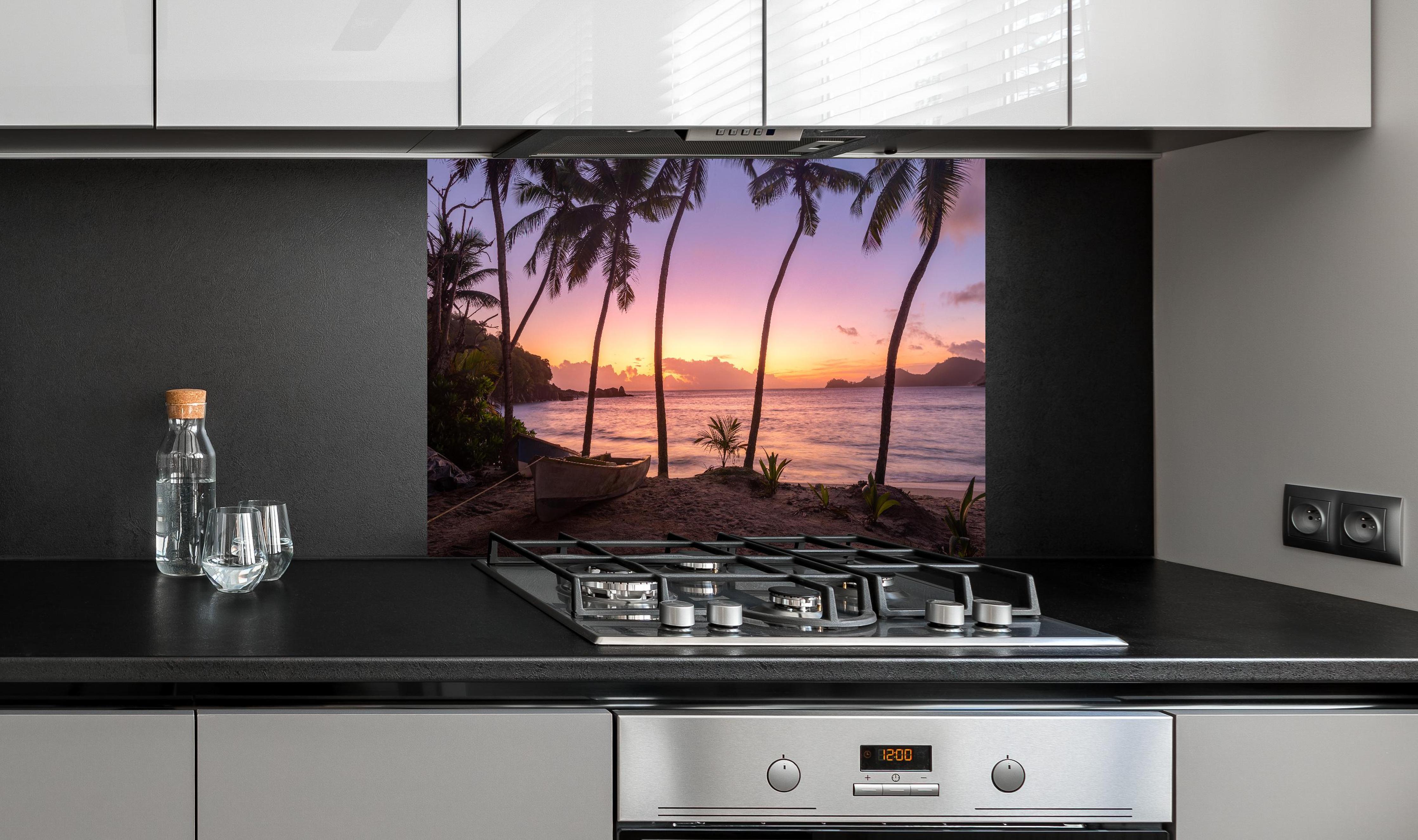 Spritzschutz - Sonnenuntergang am Strand Anse Takamaka hinter einem Cerankochfeld zwischen Holz-Kochutensilien
