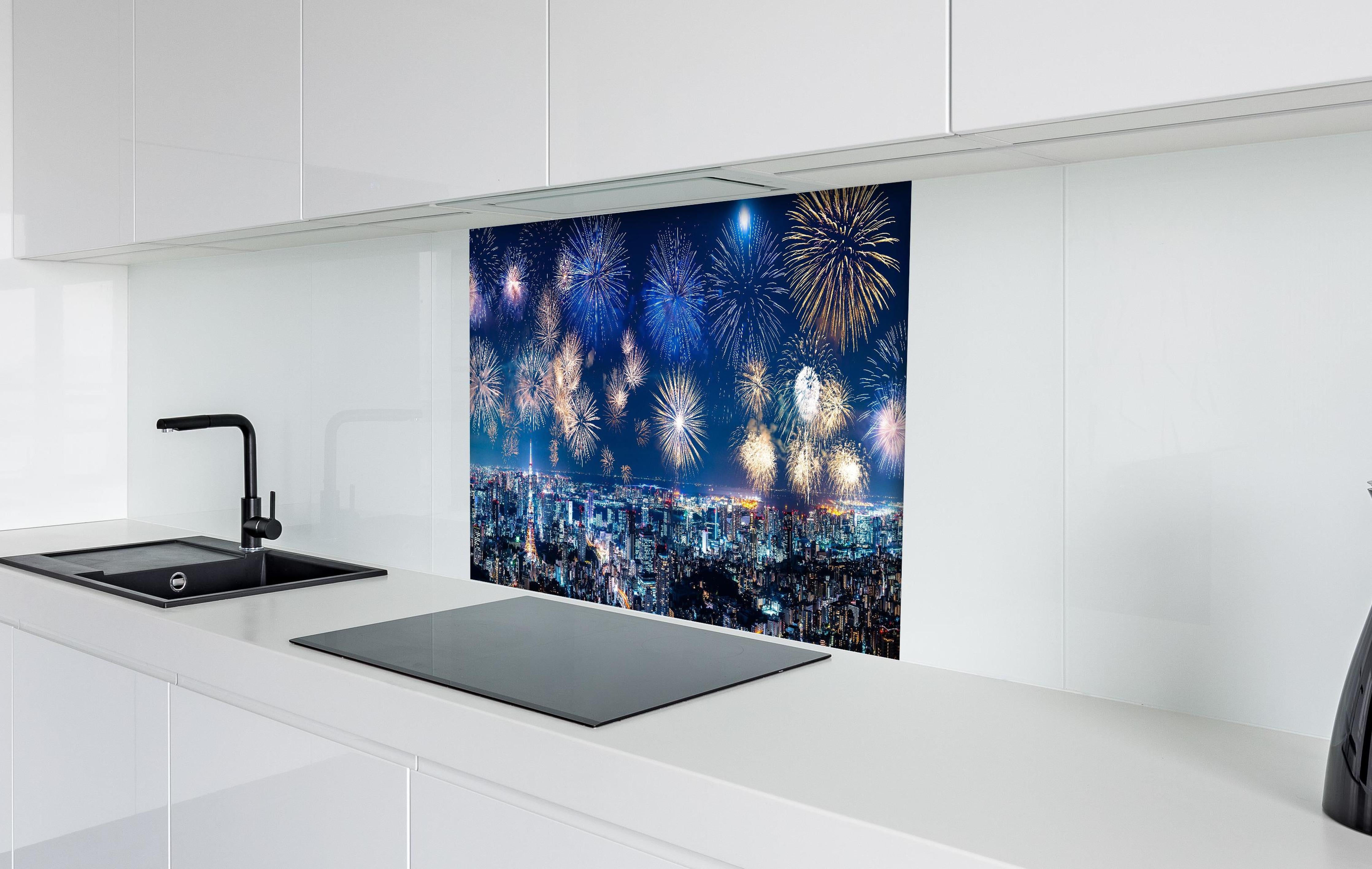 Spritzschutz - Spektakuläres Feuerwerk über Stadt bei Nacht hinter einem Cerankochfeld zwischen Holz-Kochutensilien
