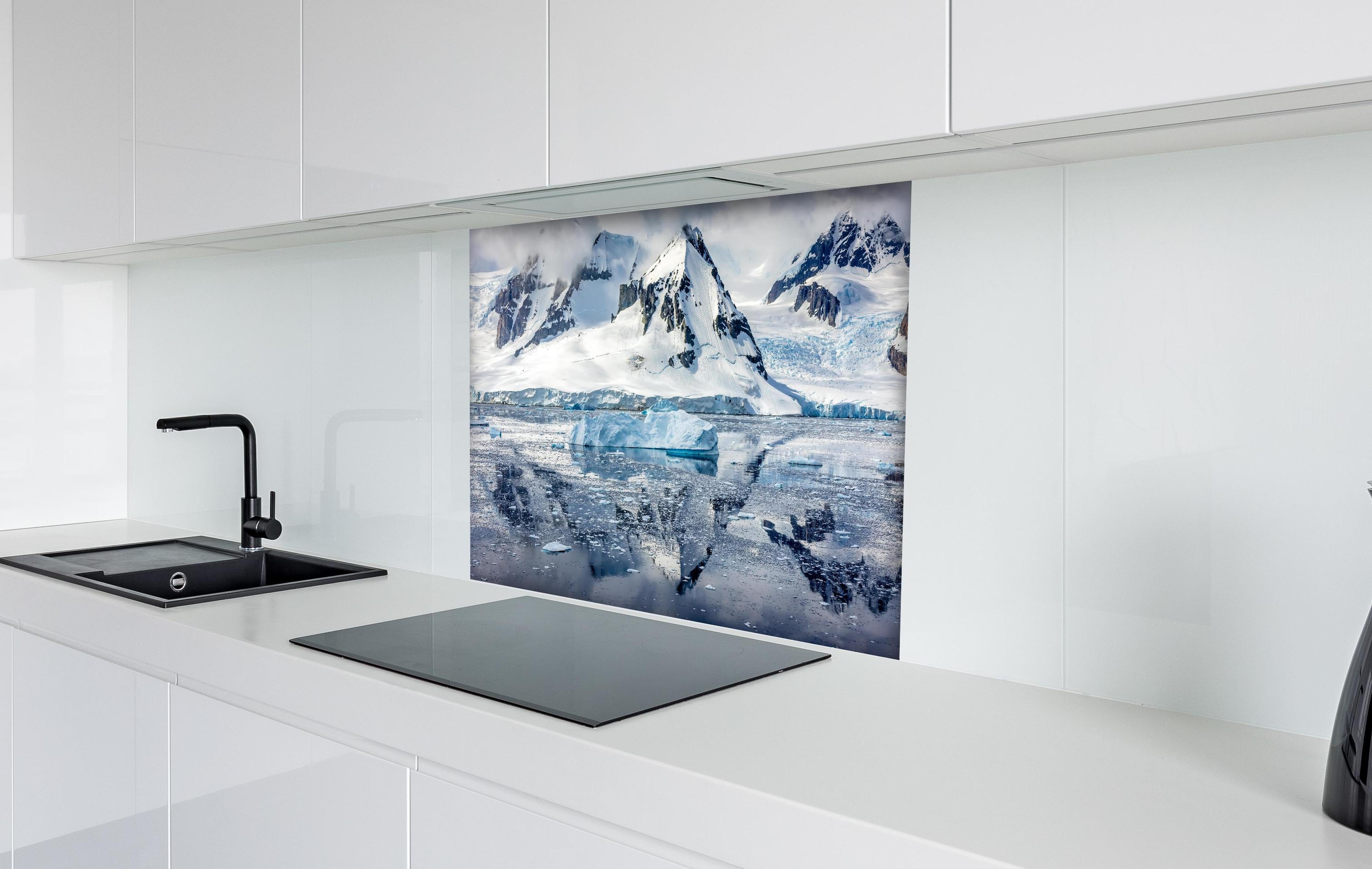 Spritzschutz - Spiegelung eines antarktischen Eisbergs hinter einem Cerankochfeld zwischen Holz-Kochutensilien
