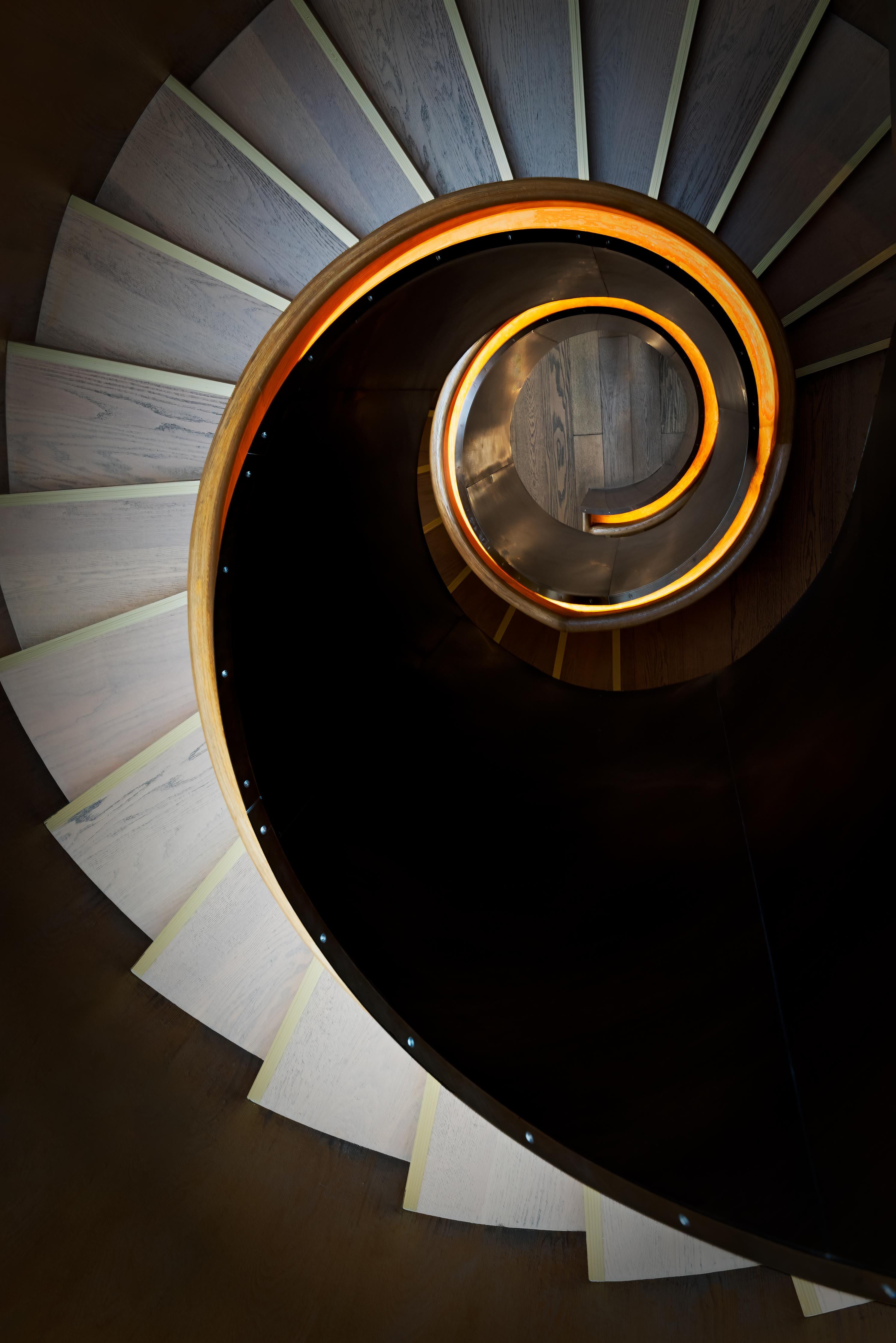 Spritzschutz-Spiraltreppe mit orangen Akzenten und dunklen Stufen