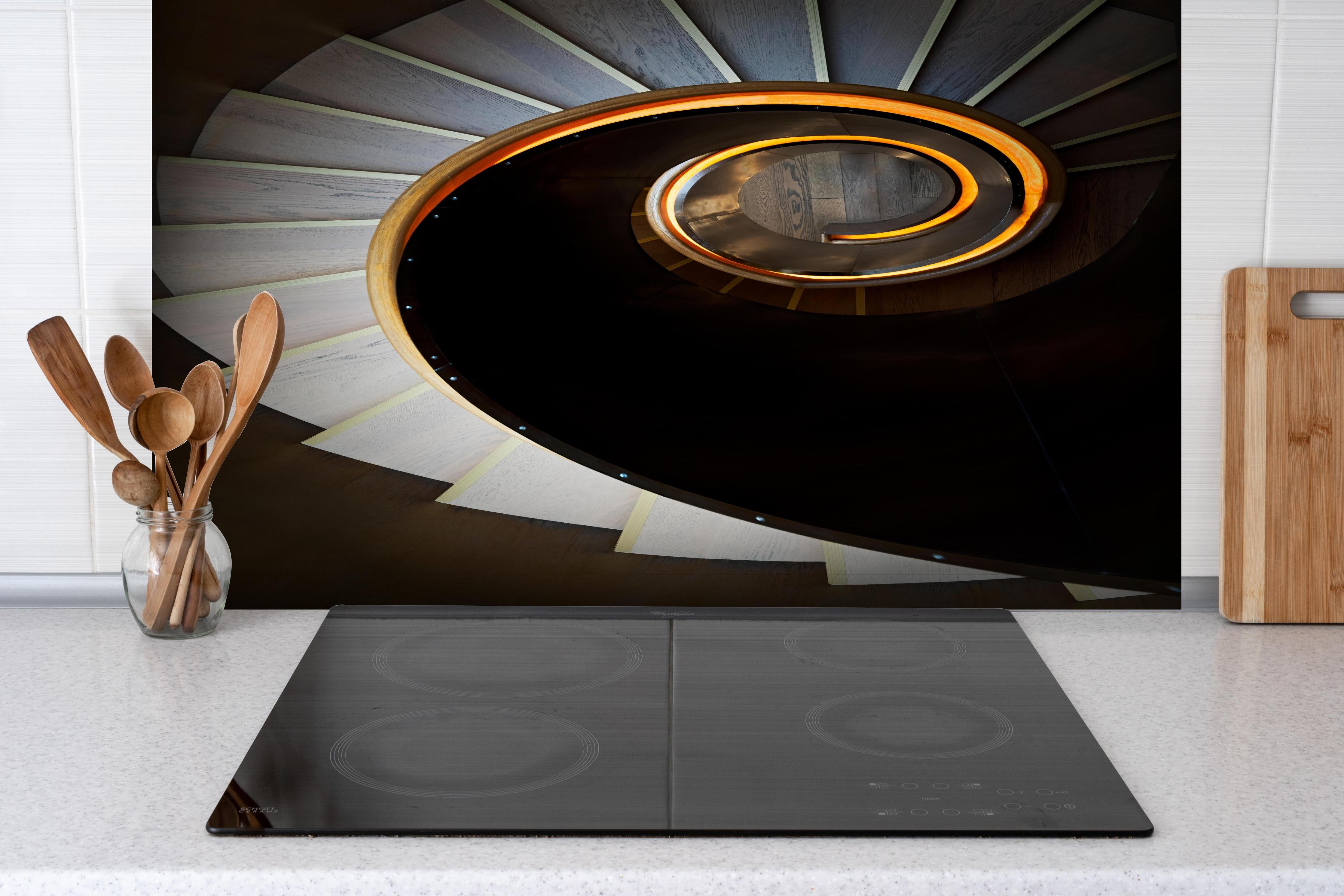 Spritzschutz - Spiraltreppe mit orangen Akzenten und dunklen Stufen hinter einem Cerankochfeld zwischen Holz-Kochutensilien
