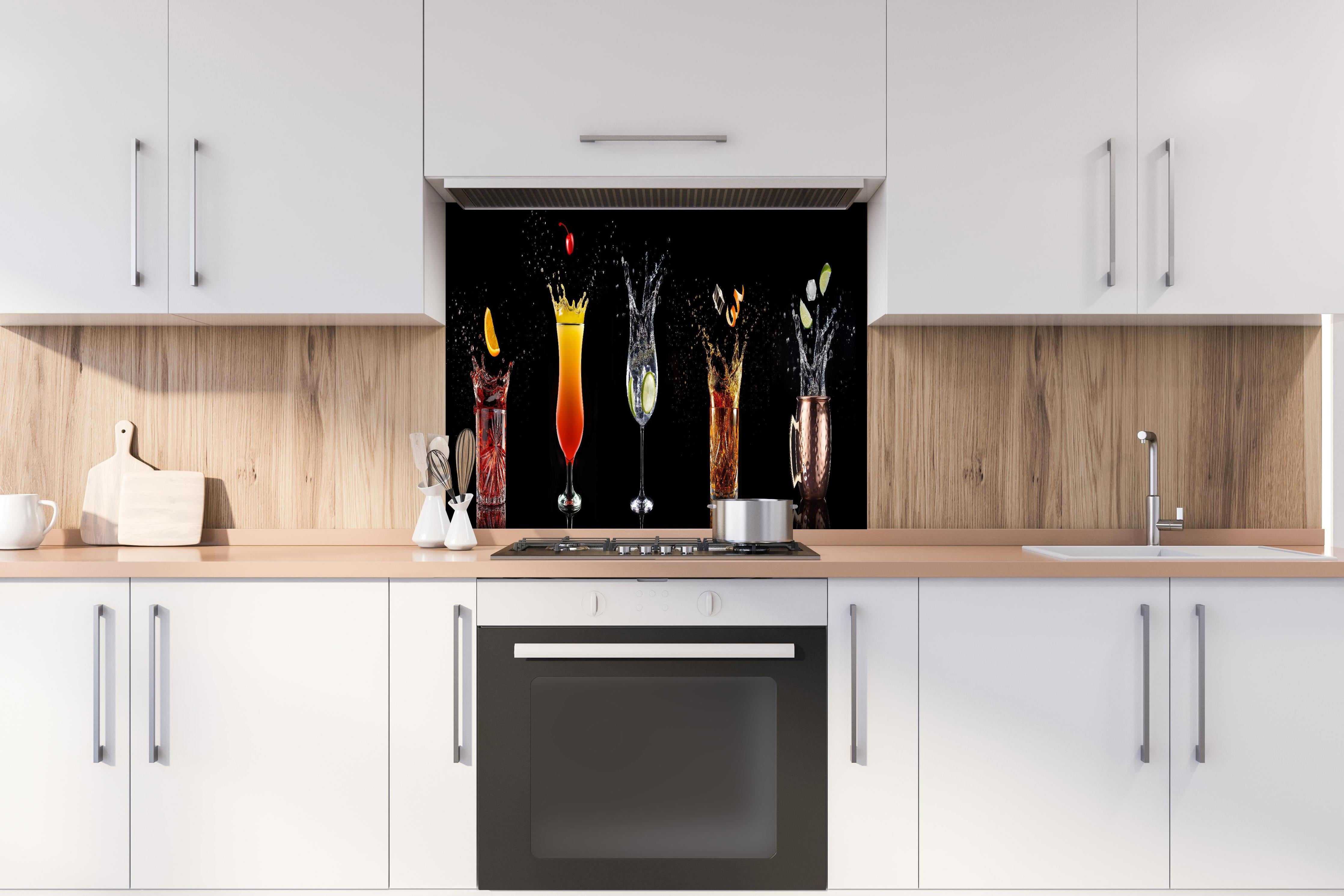 Spritzschutz - Splash-Effekt mit Cocktails auf Schwarz hinter einem Cerankochfeld zwischen Holz-Kochutensilien
