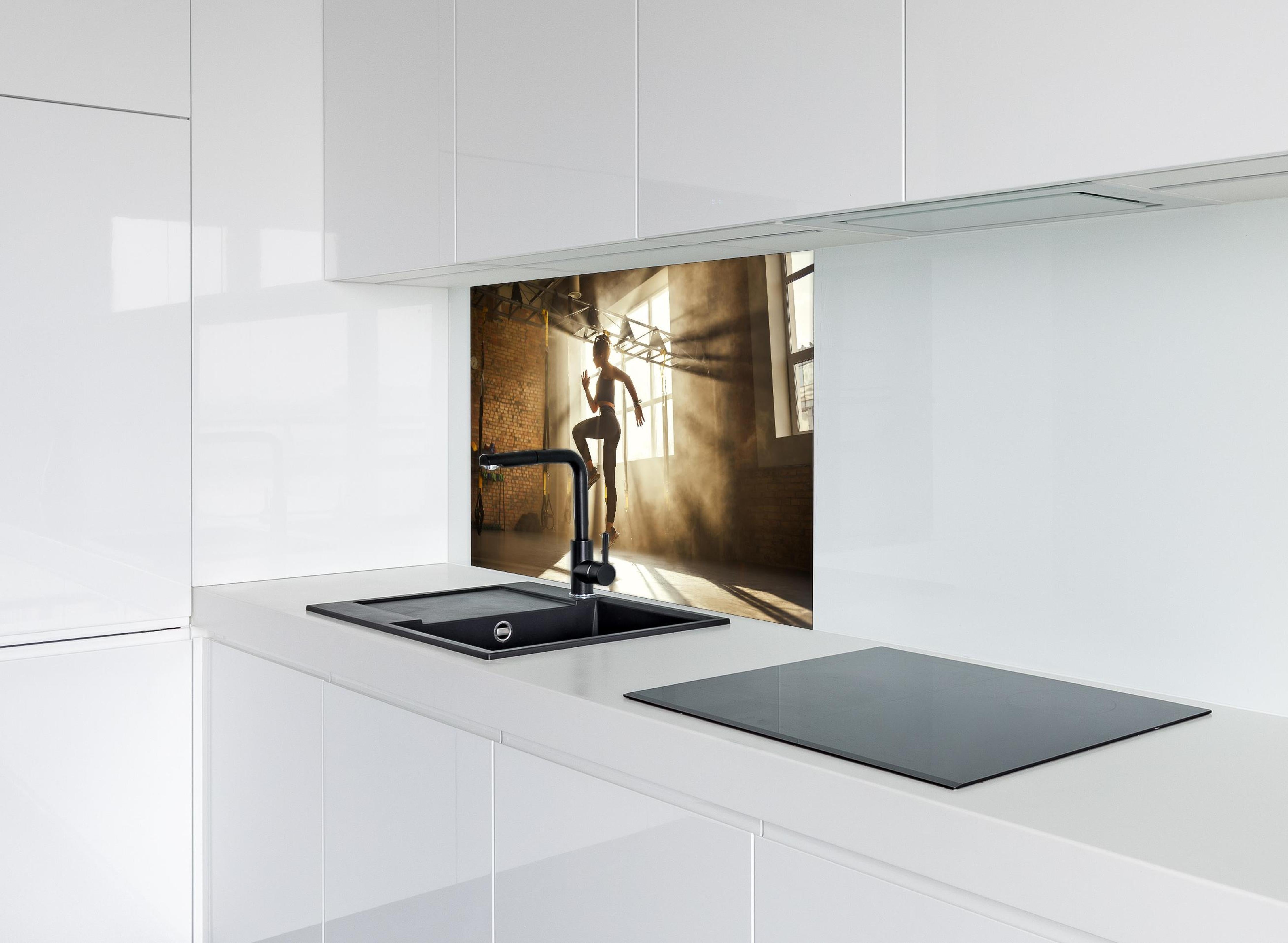 Spritzschutz - Sportlerin im Fitnesstudio hinter einem Cerankochfeld zwischen Holz-Kochutensilien
