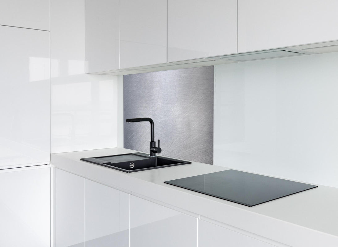 Spritzschutz -  Gebürsteter Stahl hinter modernem schwarz-matten Spülbecken in weißer Hochglanz-Küche