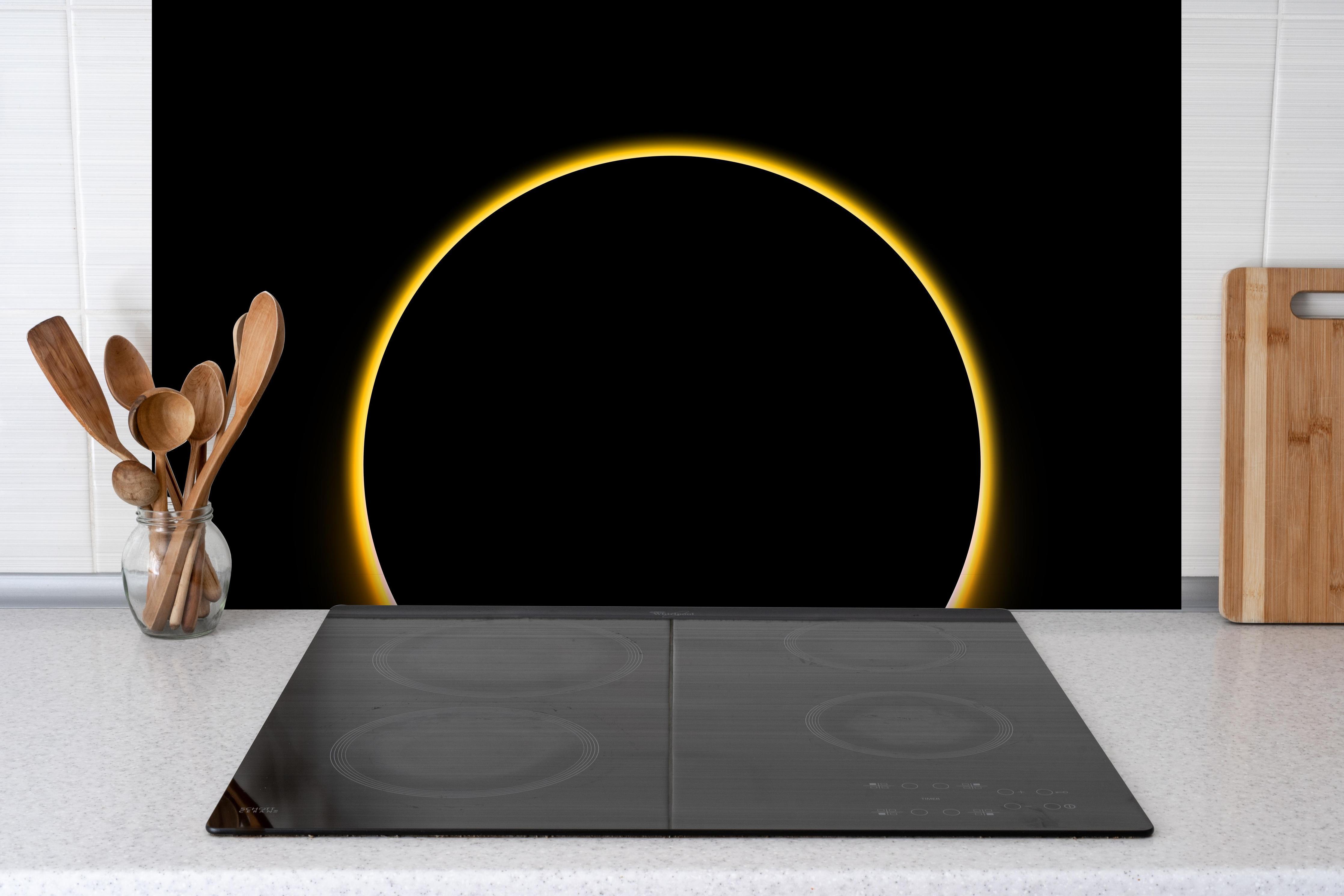 Spritzschutz -  Totale Sonnenfinsternis hinter einem Cerankochfeld zwischen Holz-Kochutensilien
