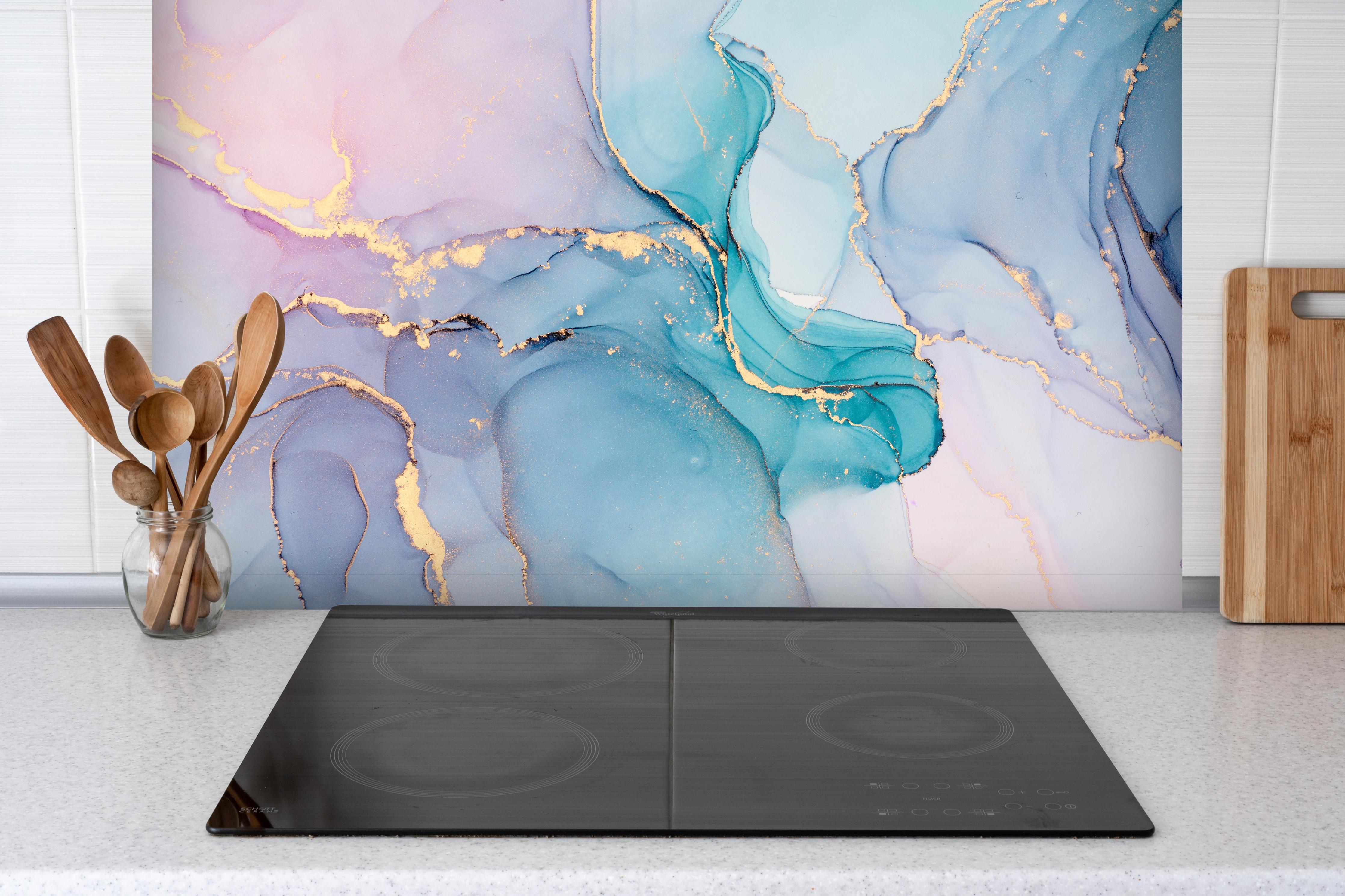 Spritzschutz - Abstrakte Muster mit goldenem Rand hinter einem Cerankochfeld zwischen Holz-Kochutensilien
