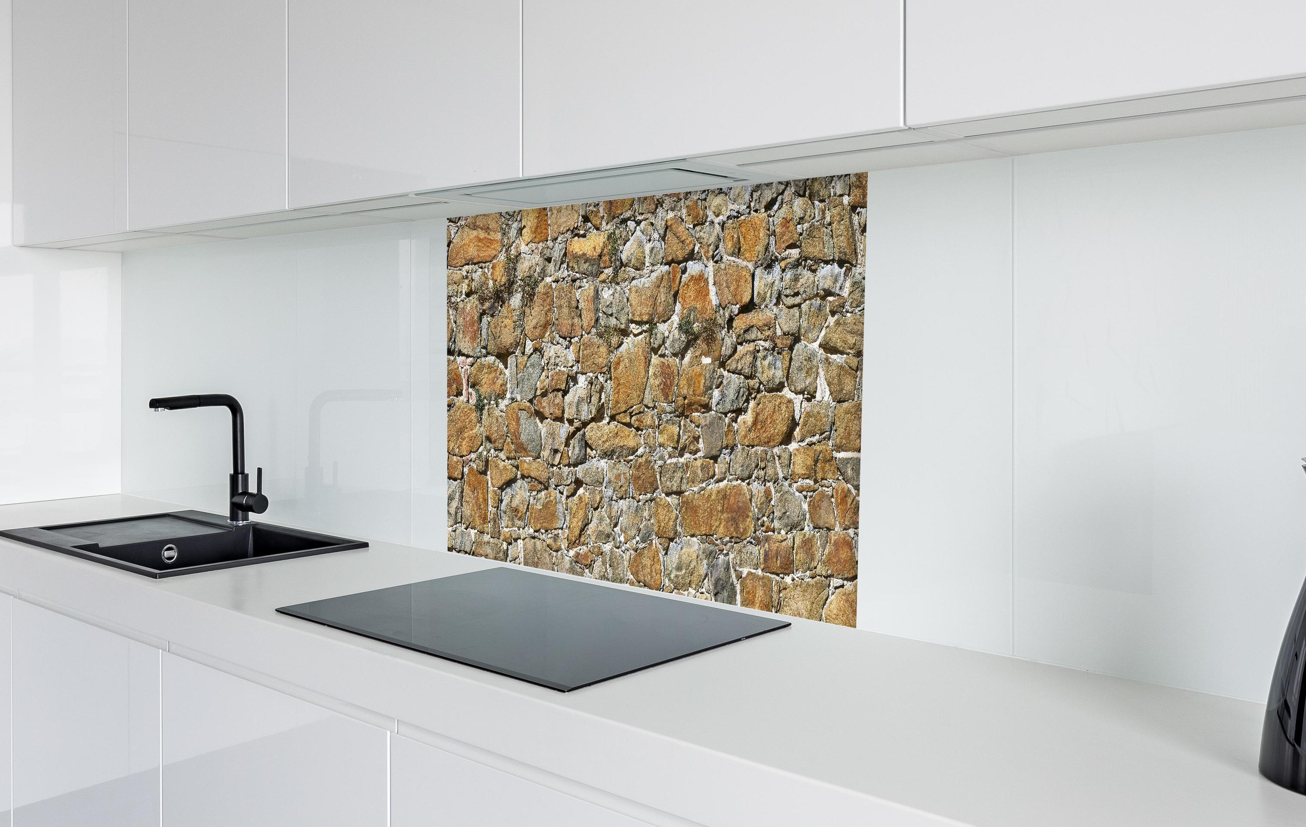 Spritzschutz - Alte unverputzte Burgmauer  in weißer Hochglanz-Küche hinter einem Cerankochfeld