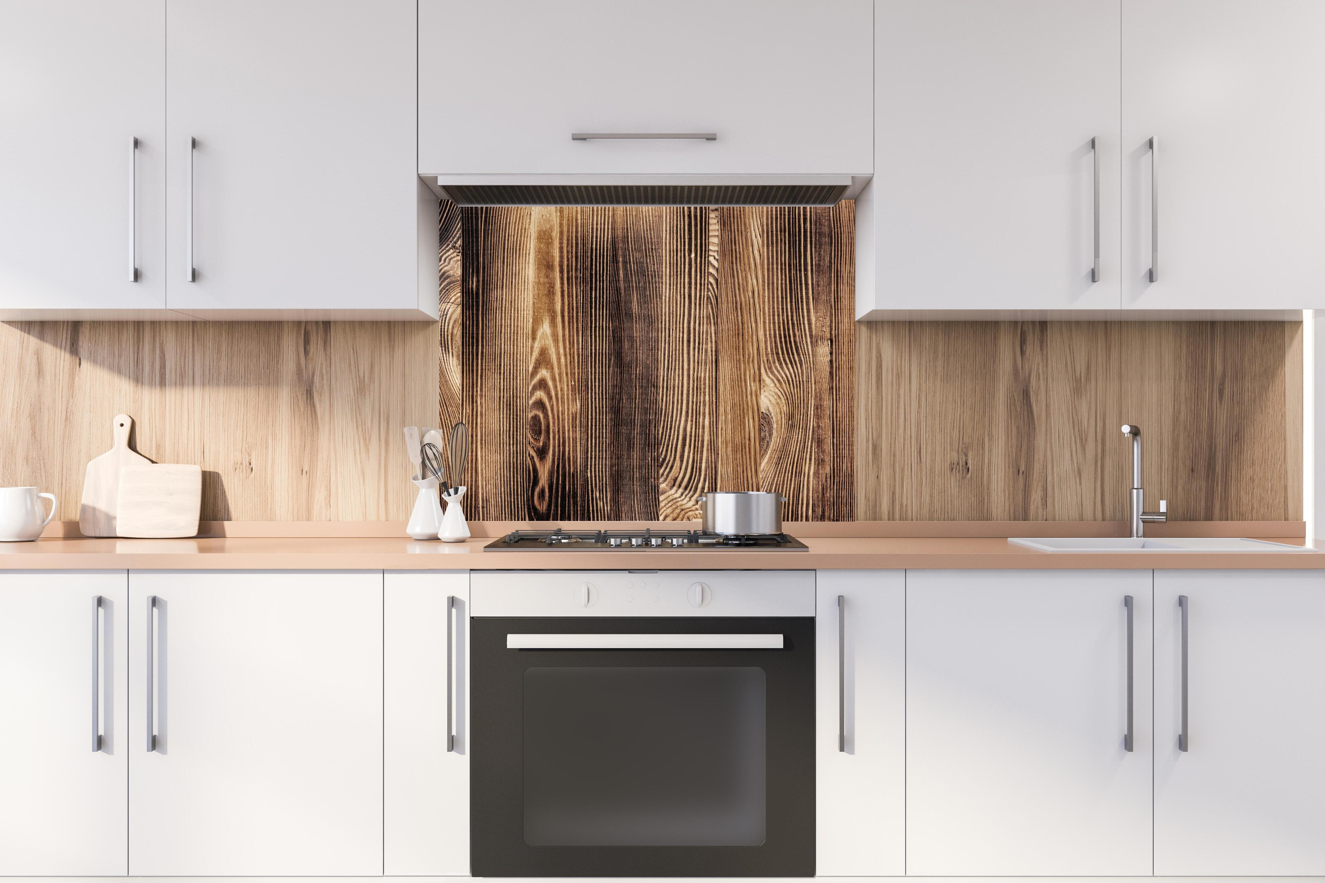 Spritzschutz - Angebrannte Naturholzplatte hinter stilvollem Gasherd unter Dunstabzugshaube