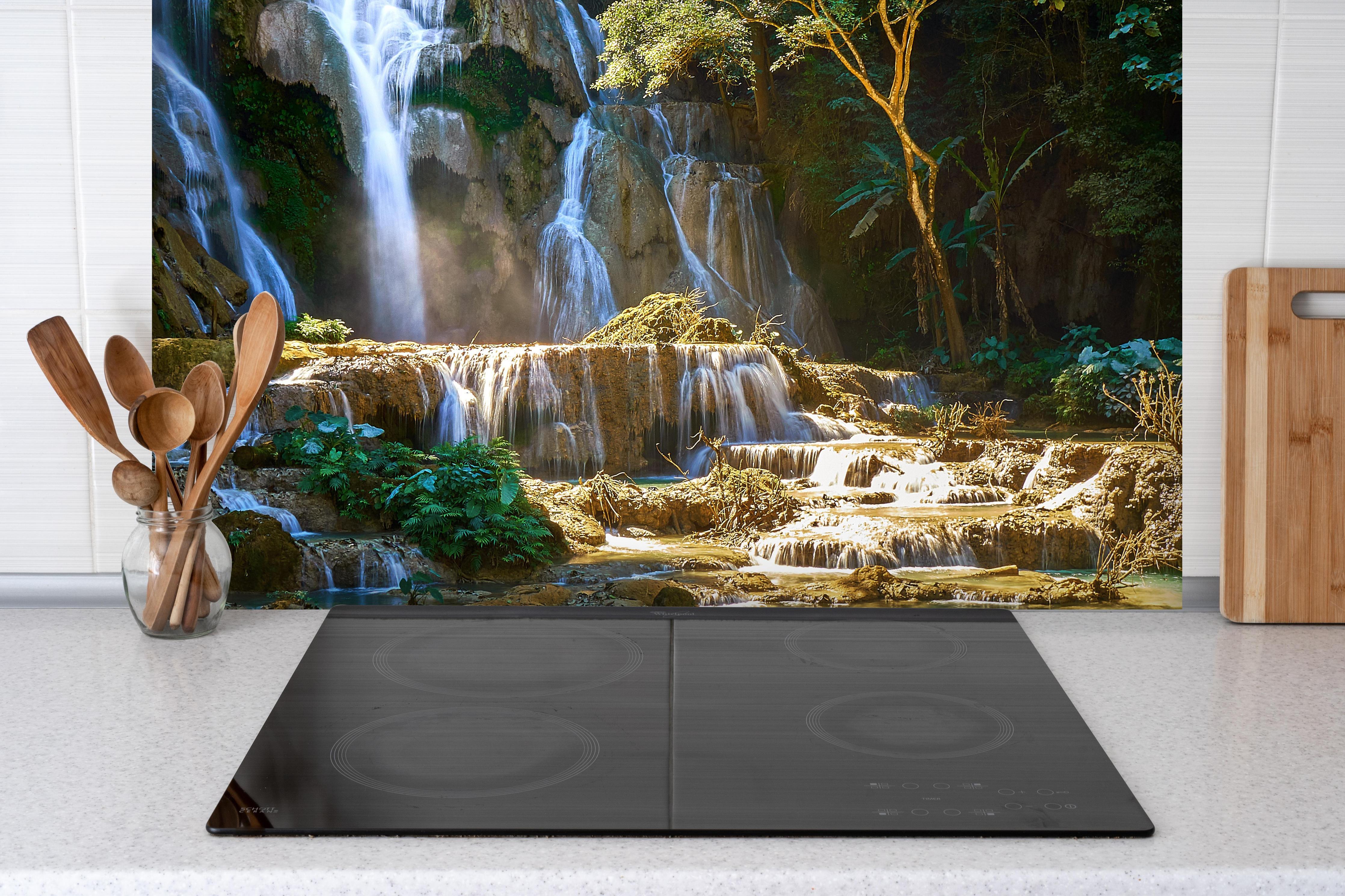 Spritzschutz - Atemberaubender Wasserfall in Laos hinter einem Cerankochfeld zwischen Holz-Kochutensilien
