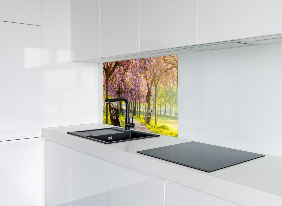 Spritzschutz - Bänke unter Kirschblütenbäumen hinter modernem schwarz-matten Spülbecken in weißer Hochglanz-Küche