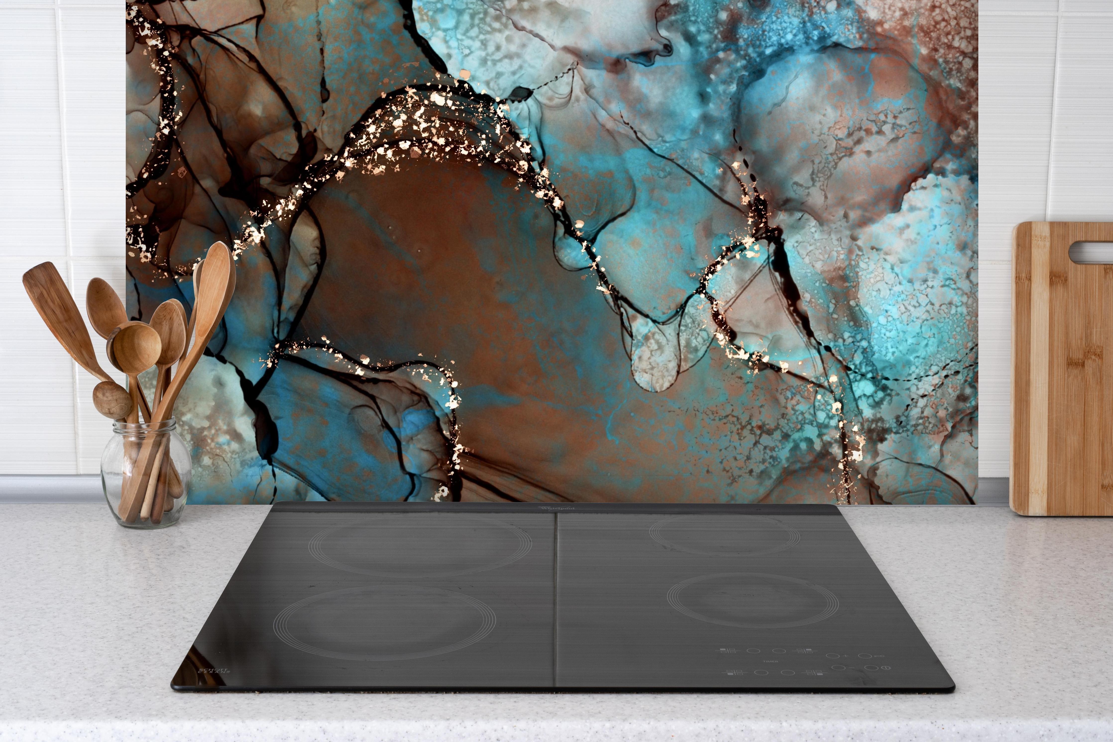 Spritzschutz - Bläulich flüssige Tinte mit Goldelementen hinter einem Cerankochfeld zwischen Holz-Kochutensilien
