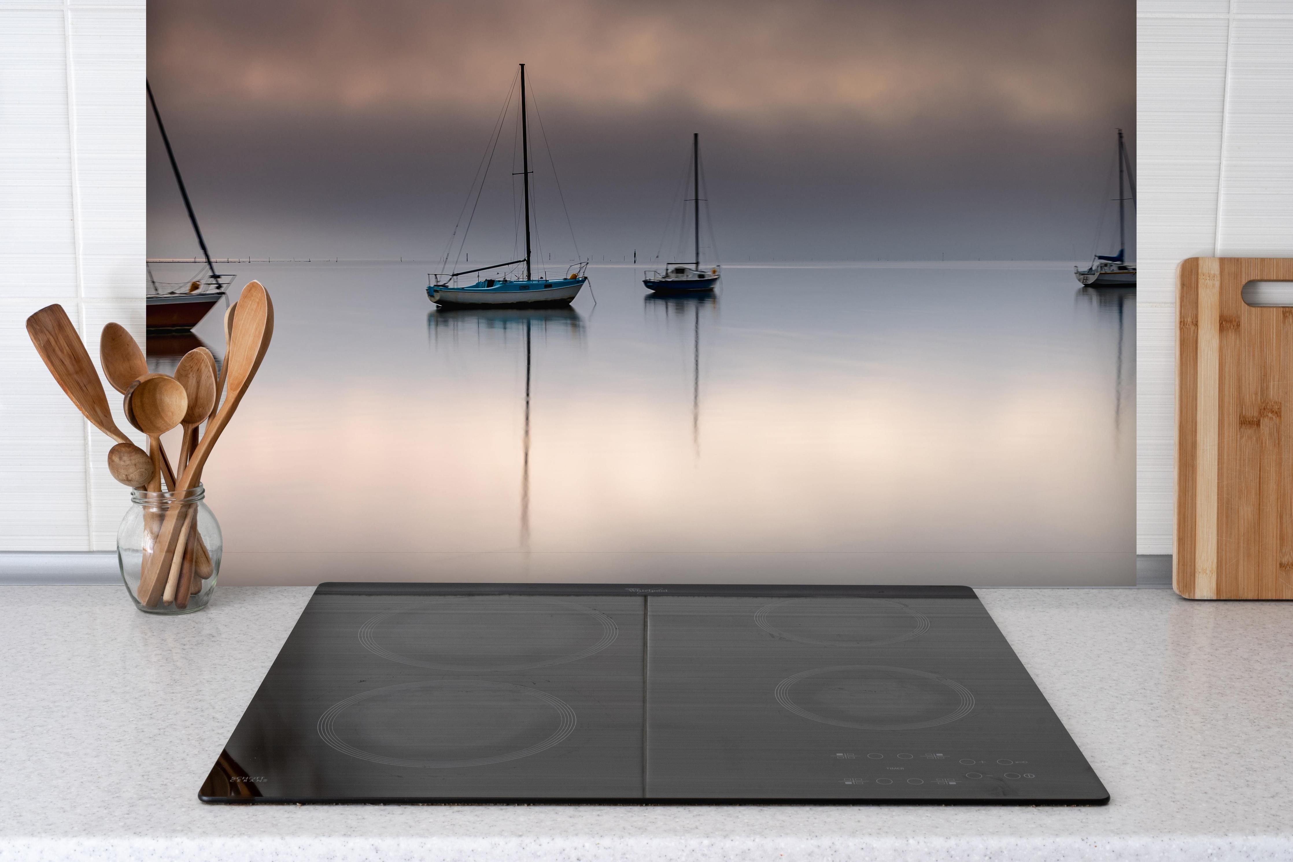 Spritzschutz - Boote auf nebeligem Meer hinter einem Cerankochfeld zwischen Holz-Kochutensilien
