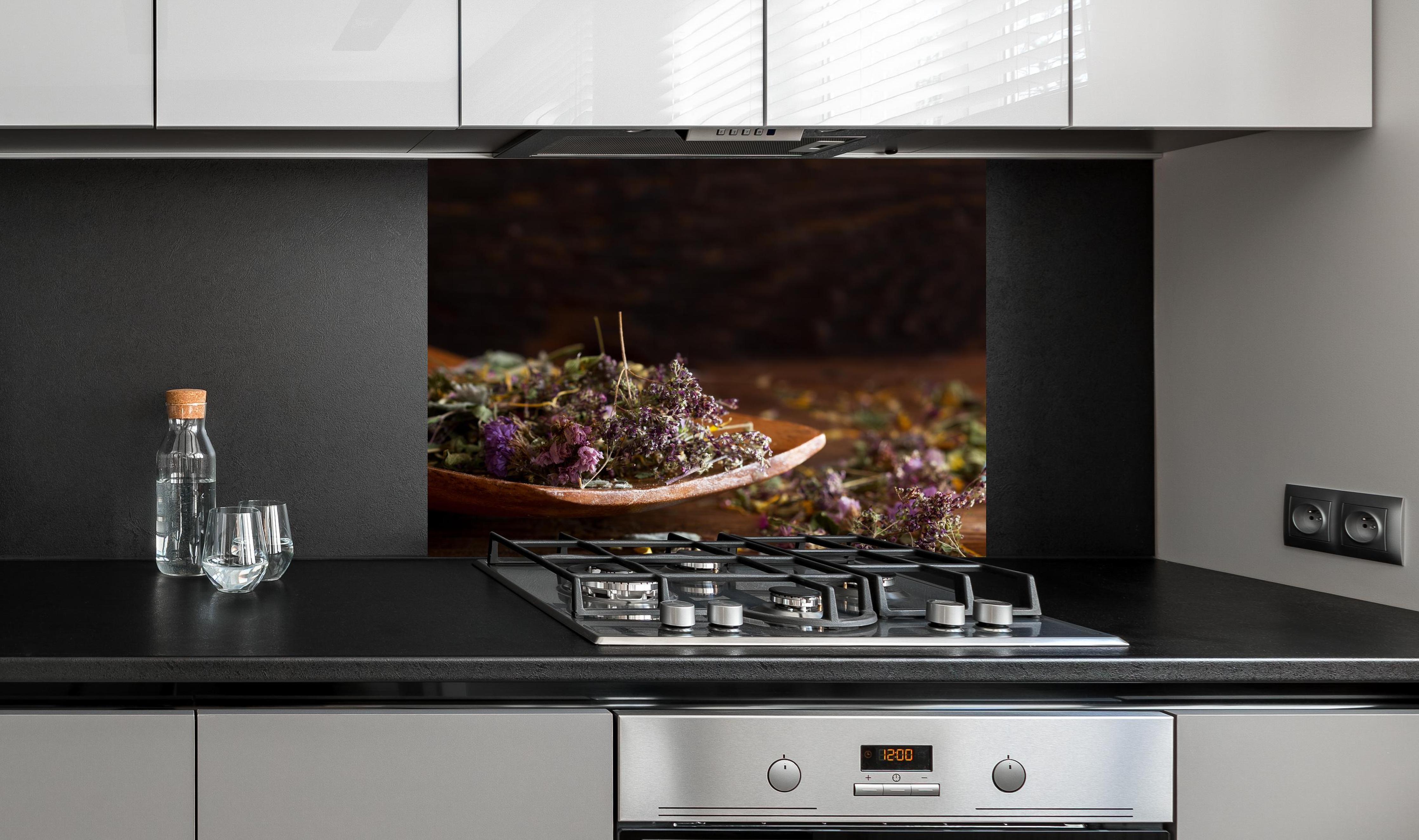 Spritzschutz - Dampfende Tasse Tee mit Kräutern an edler Anthrazit-Wand hinter silbernem Gasherd