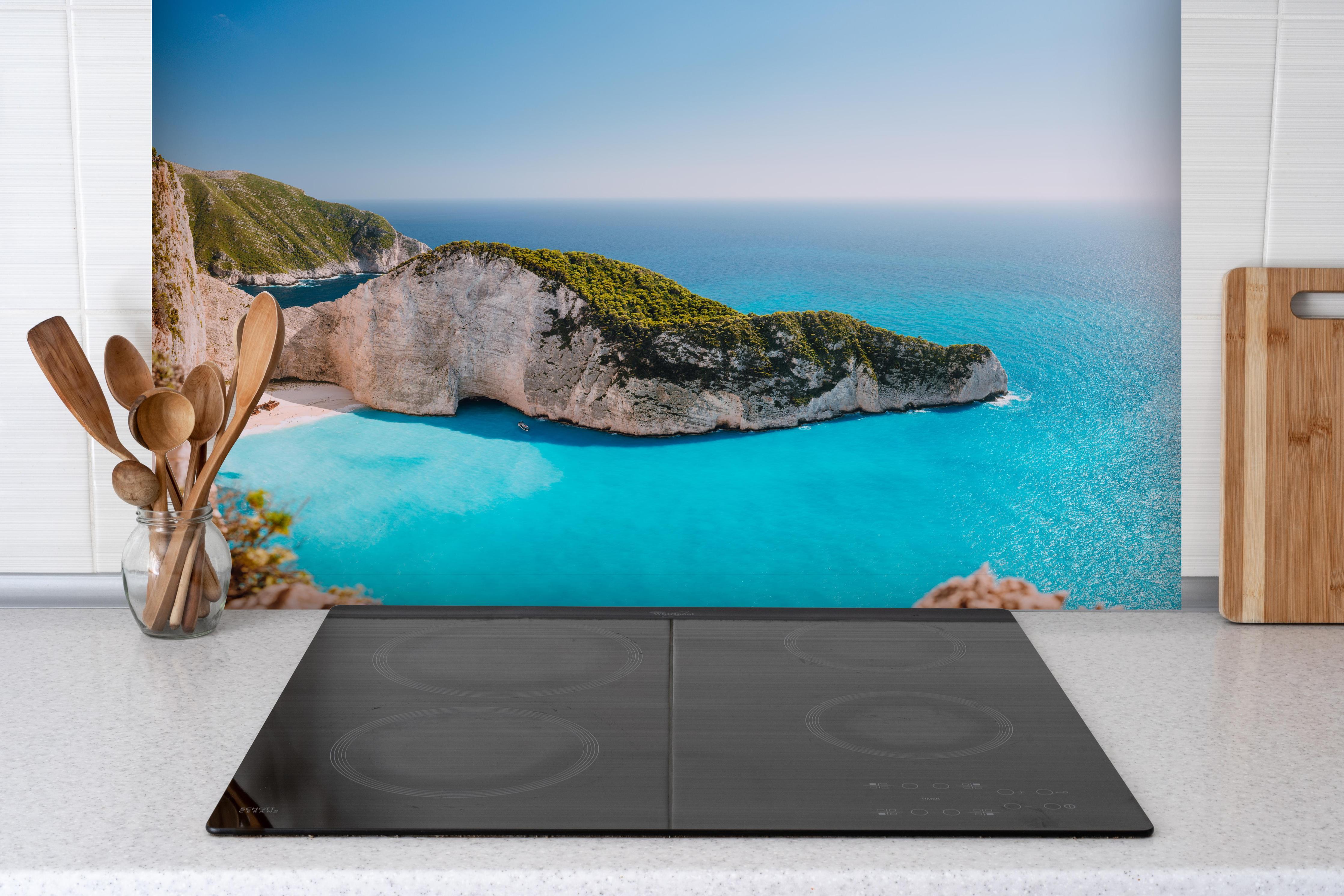 Spritzschutz - Der Strand von Navagio - Griechenland hinter einem Cerankochfeld zwischen Holz-Kochutensilien
