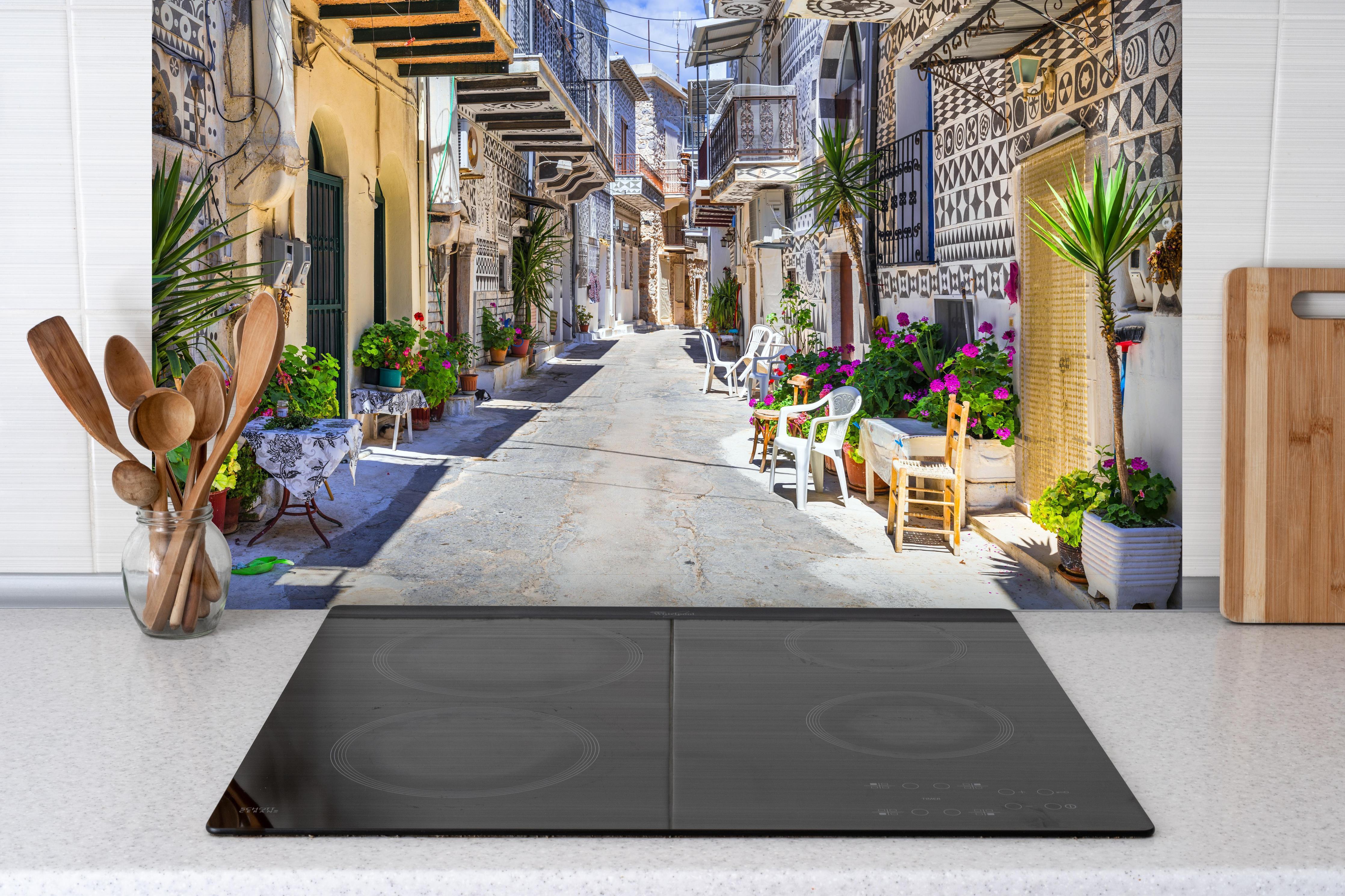 Spritzschutz - Dorf Pyrgi in Griechenland hinter einem Cerankochfeld zwischen Holz-Kochutensilien
