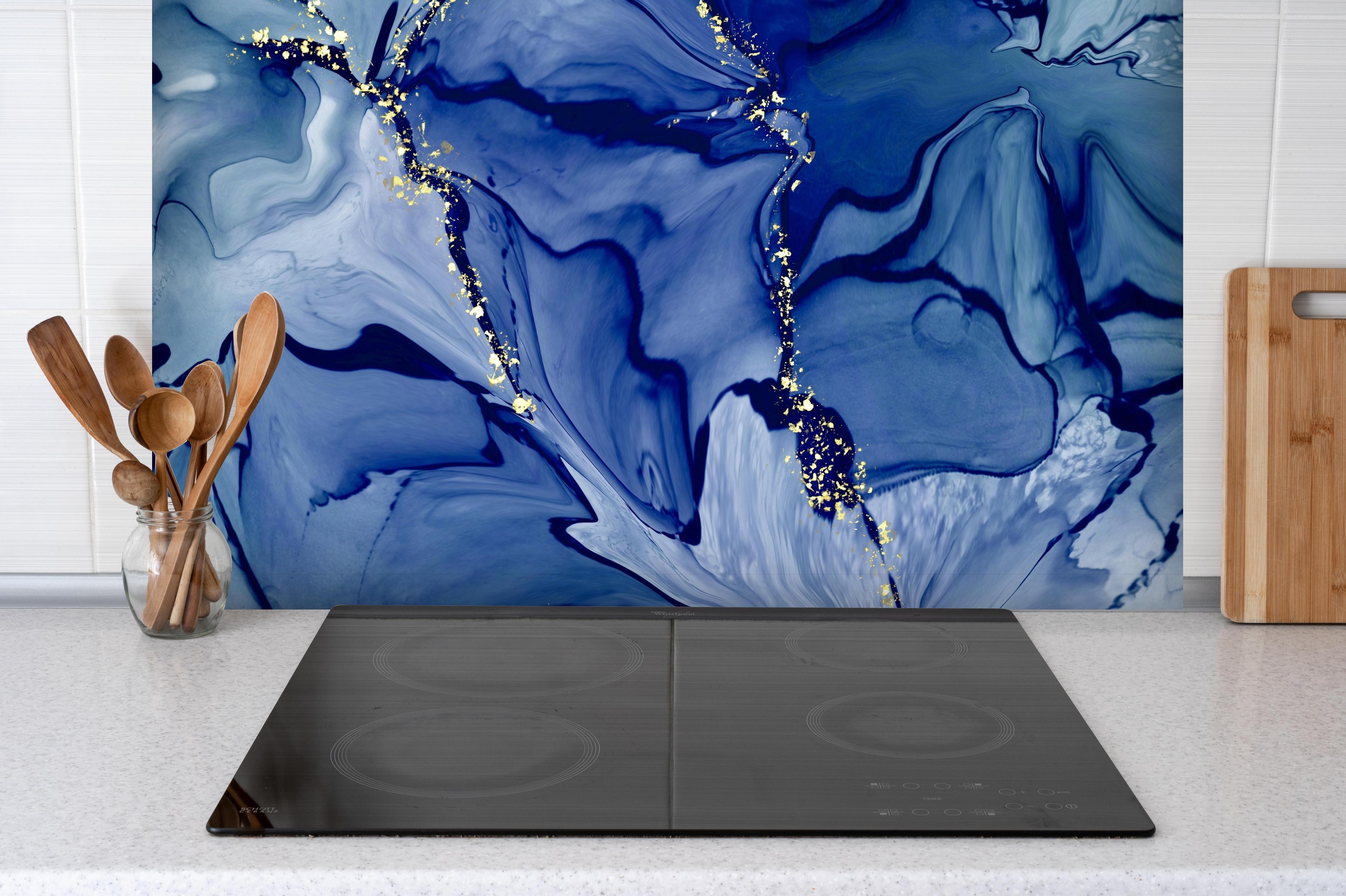 Spritzschutz - Dunkelblaue Tinte mit Goldelementen hinter einem Cerankochfeld zwischen Holz-Kochutensilien
