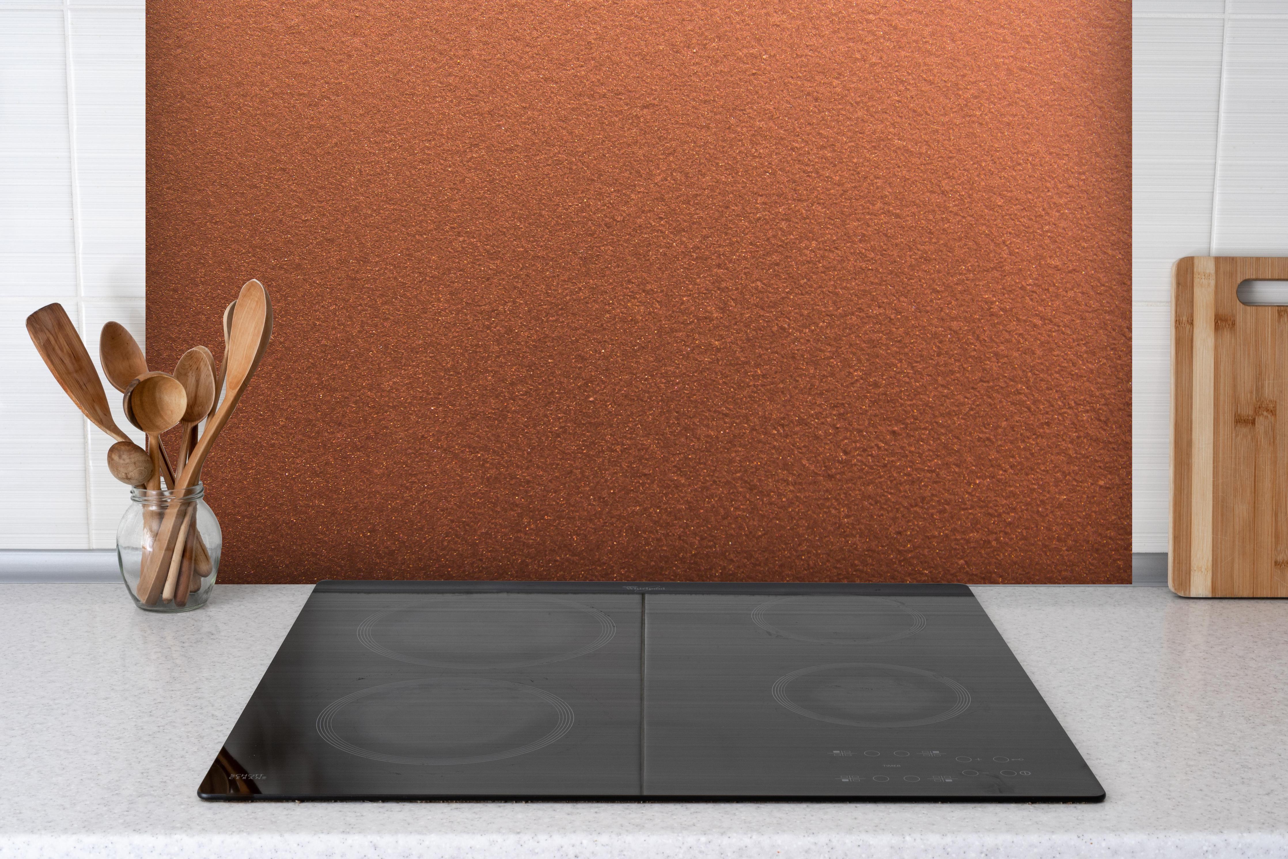 Spritzschutz - Dunkles blasses Bronze hinter einem Cerankochfeld zwischen Holz-Kochutensilien
