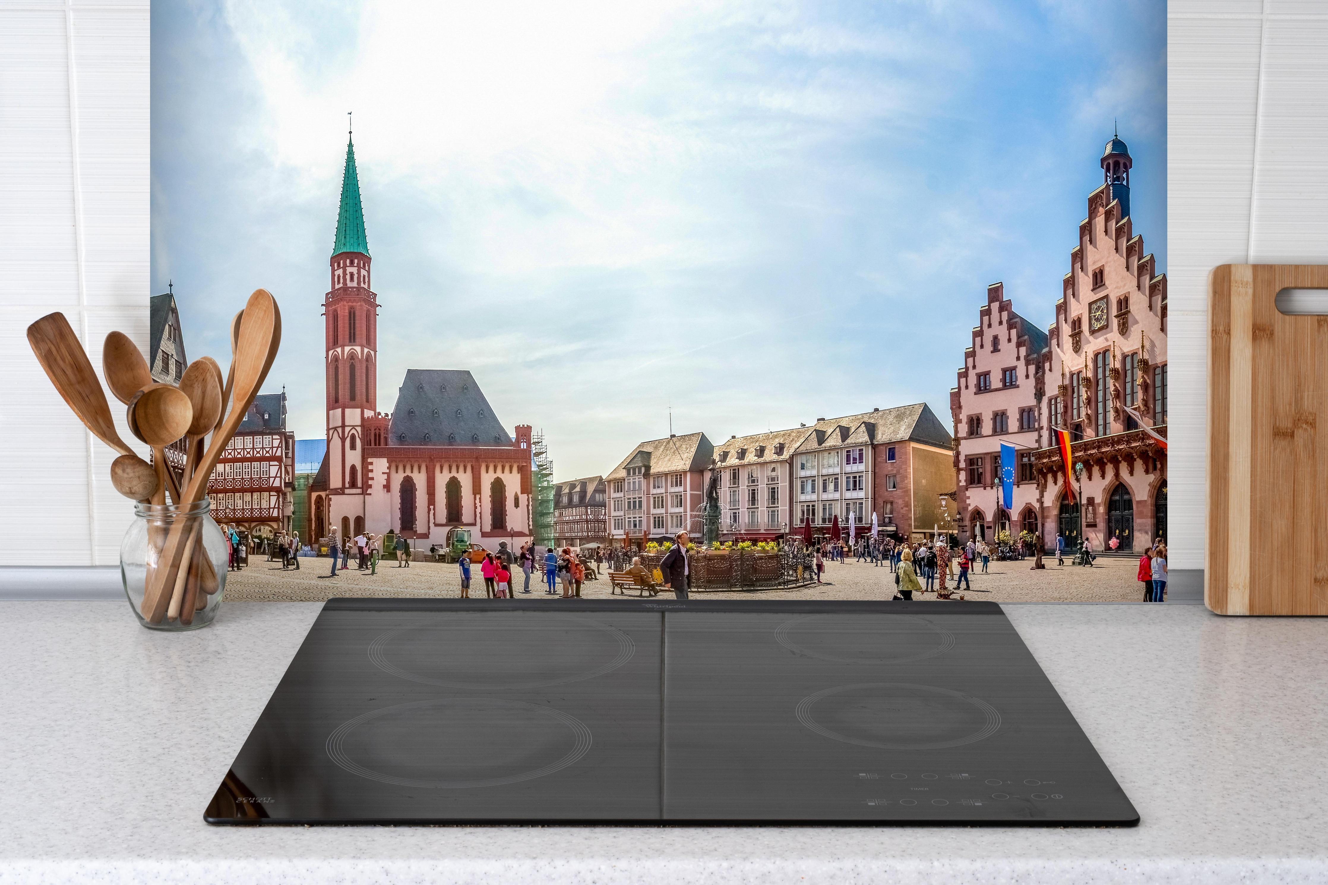 Spritzschutz - Frankfurter Römer bei Tag hinter einem Cerankochfeld zwischen Holz-Kochutensilien
