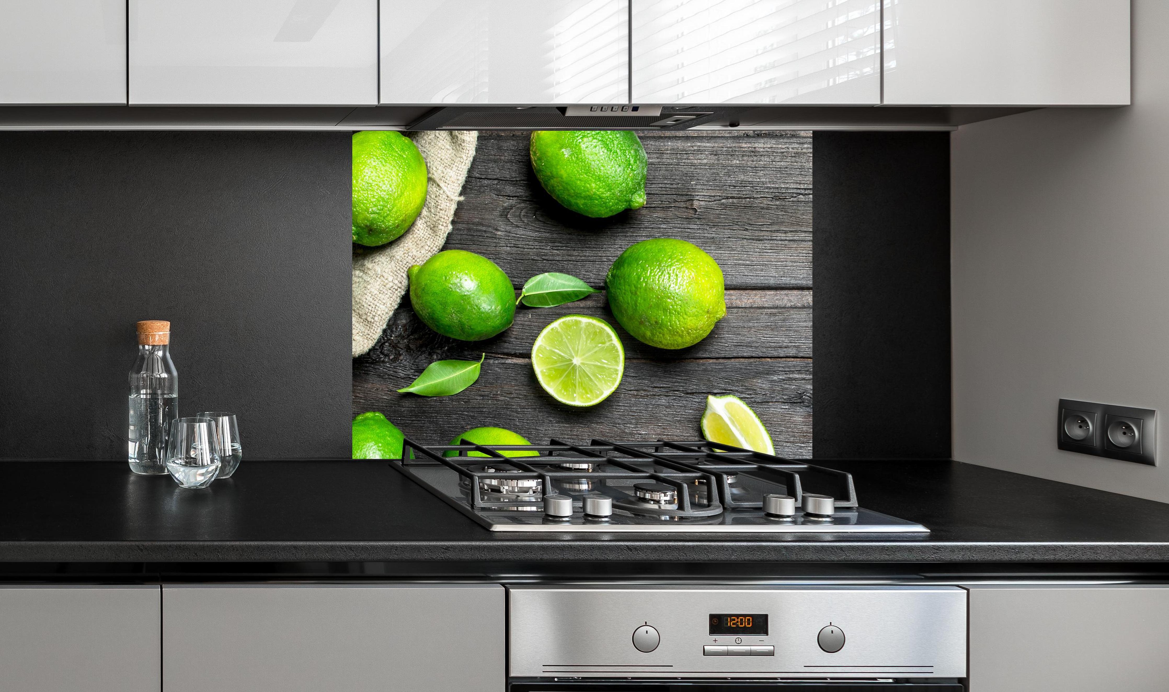 Spritzschutz - Frisch geerntete Limetten an edler Anthrazit-Wand hinter silbernem Gasherd