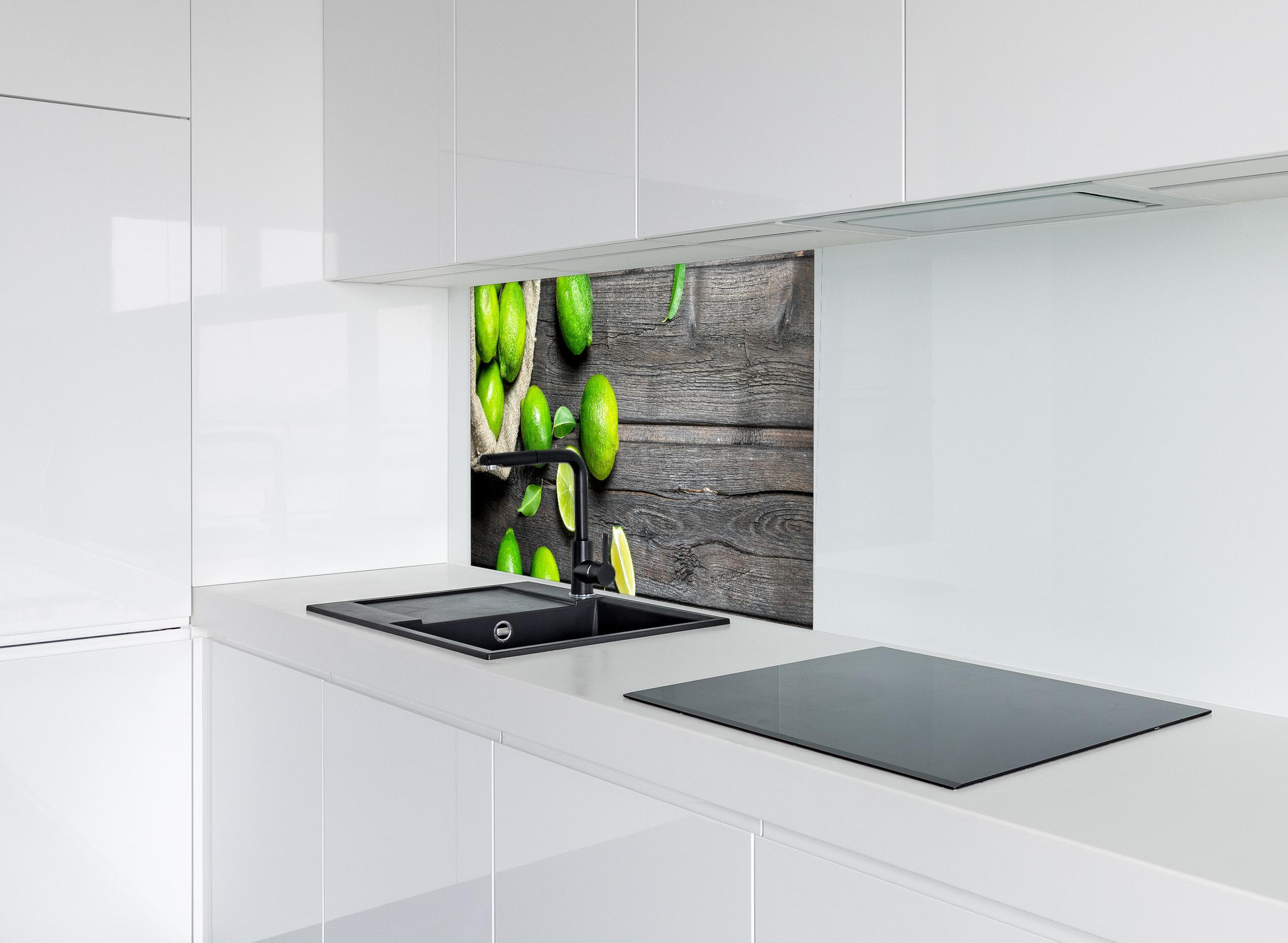 Spritzschutz - Frisch geerntete Limetten hinter modernem schwarz-matten Spülbecken in weißer Hochglanz-Küche